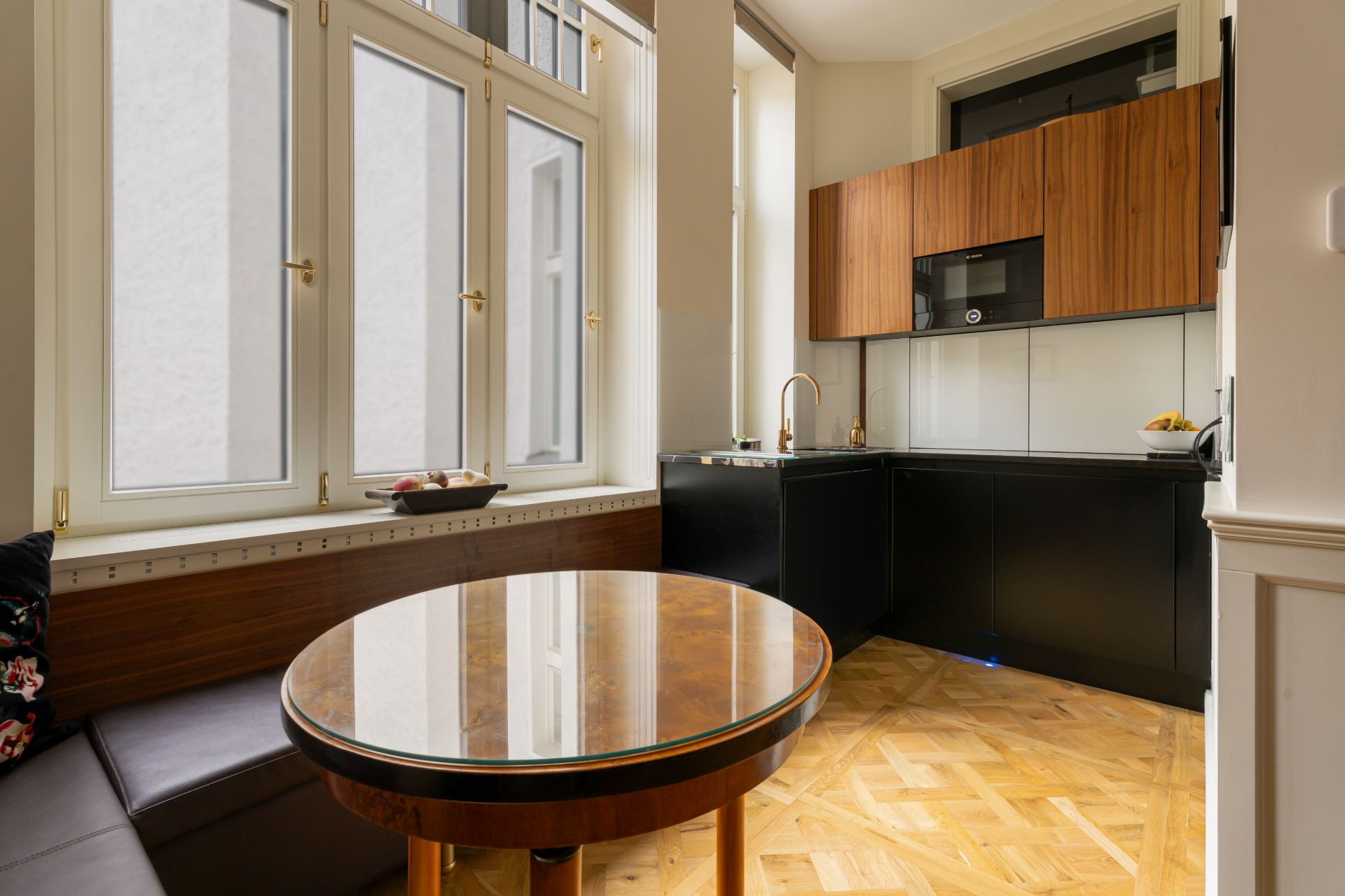 Moderne Küche mit rundem Holztisch, Eckbank und großen Fenstern.