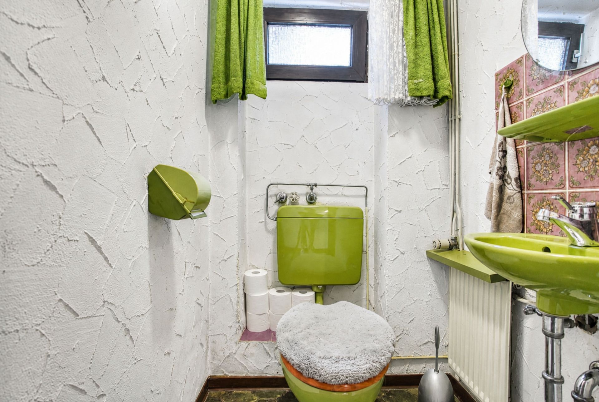 Kleines Badezimmer mit grüner Toilette, grünem Waschbecken und grünen Vorhängen.