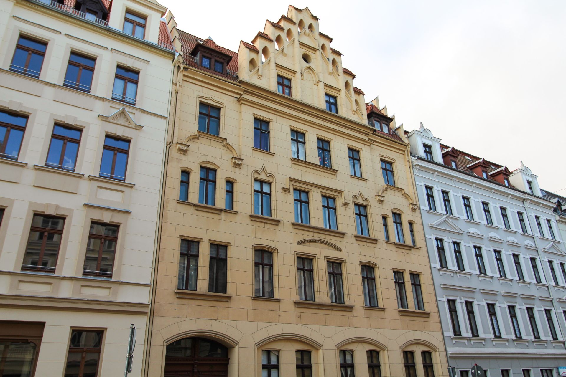 Mehrstöckiges Wohngebäude mit gelber Fassade und zahlreichen Fenstern.