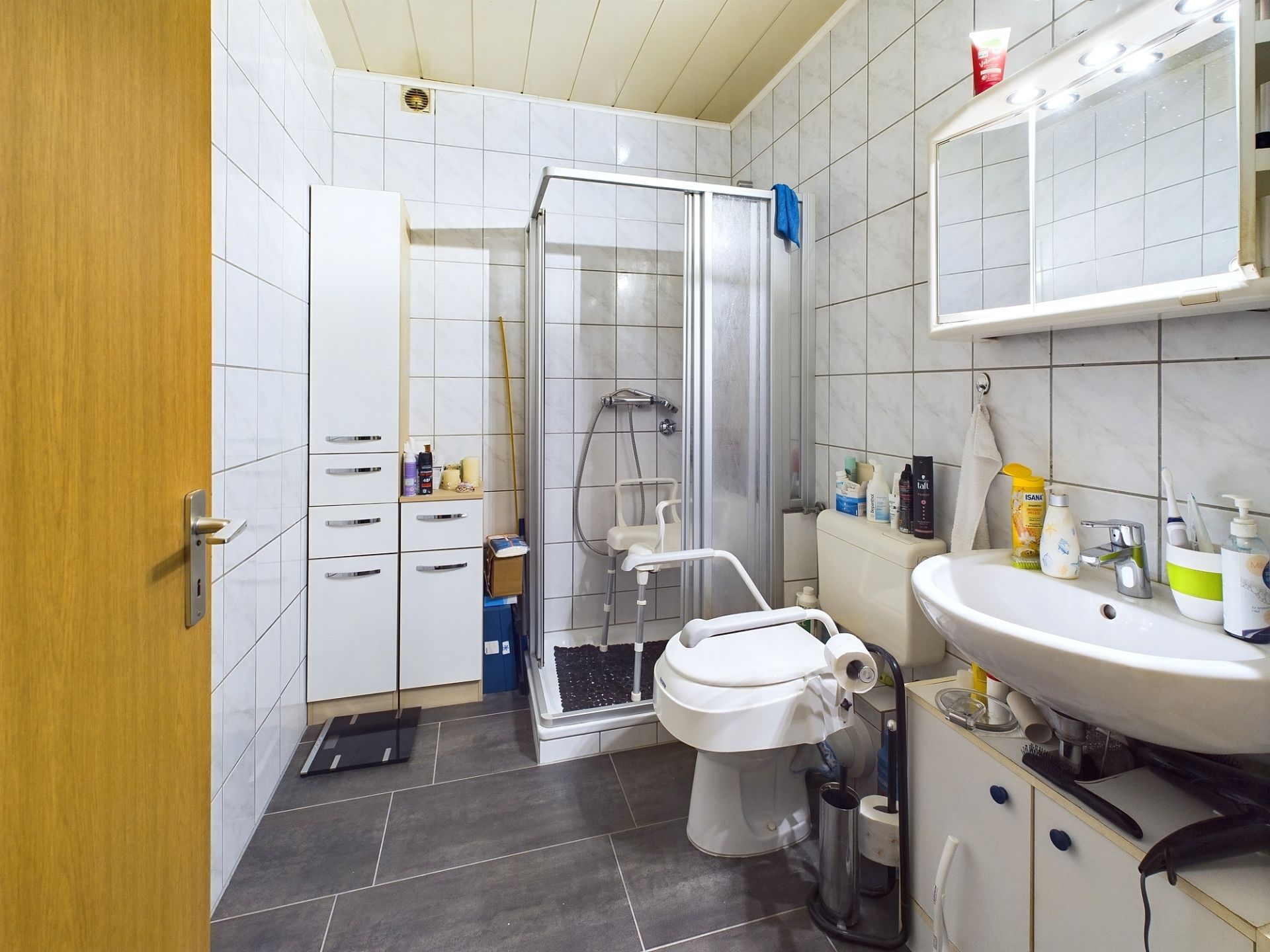 Badezimmer mit Dusche, Waschbecken, Toilette und weißem Spiegelschrank.