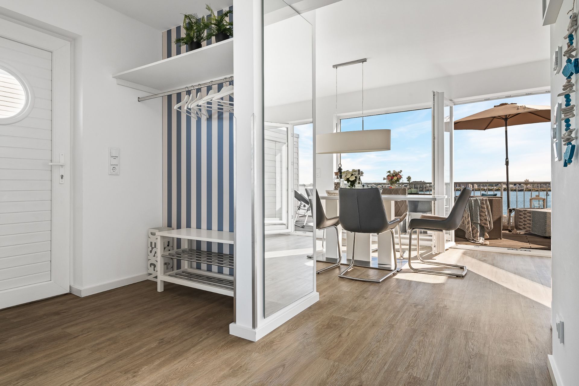 Heller Flur mit Garderobe, Essbereich und Zugang zu einem Balkon mit Seeblick.