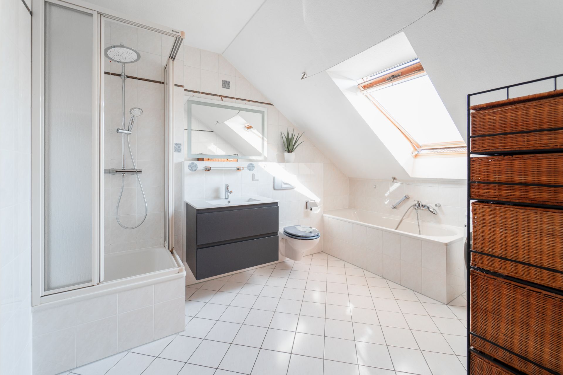 Modernes Badezimmer mit Dusche, Badewanne, Waschbecken, WC und Dachfenster.