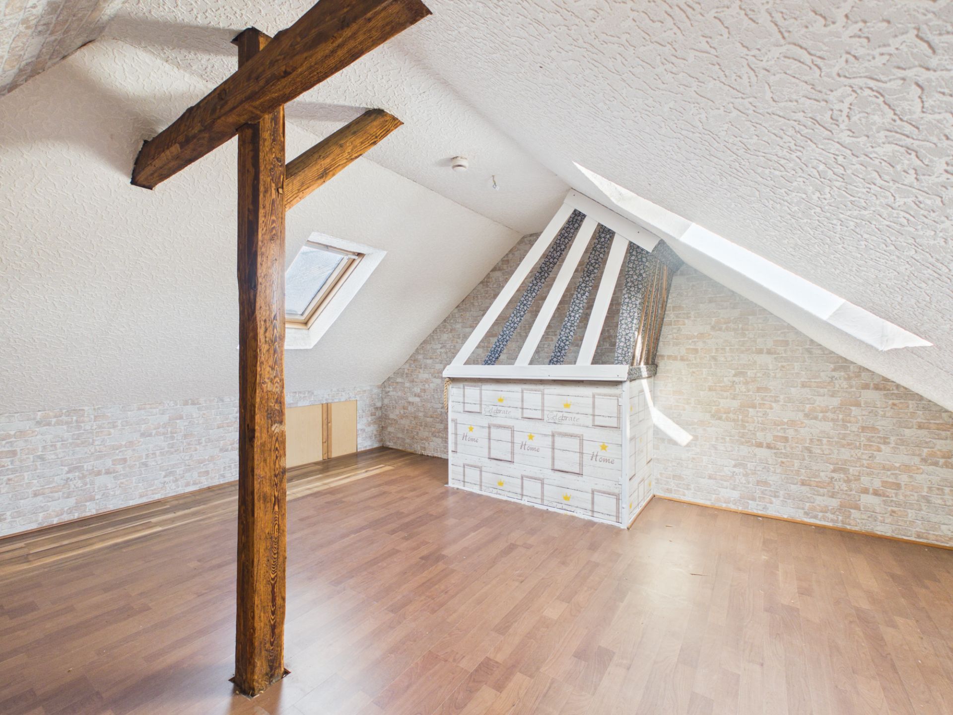 Heller Dachbodenraum mit Holzbalken, Dachfenstern und Holzfußboden.