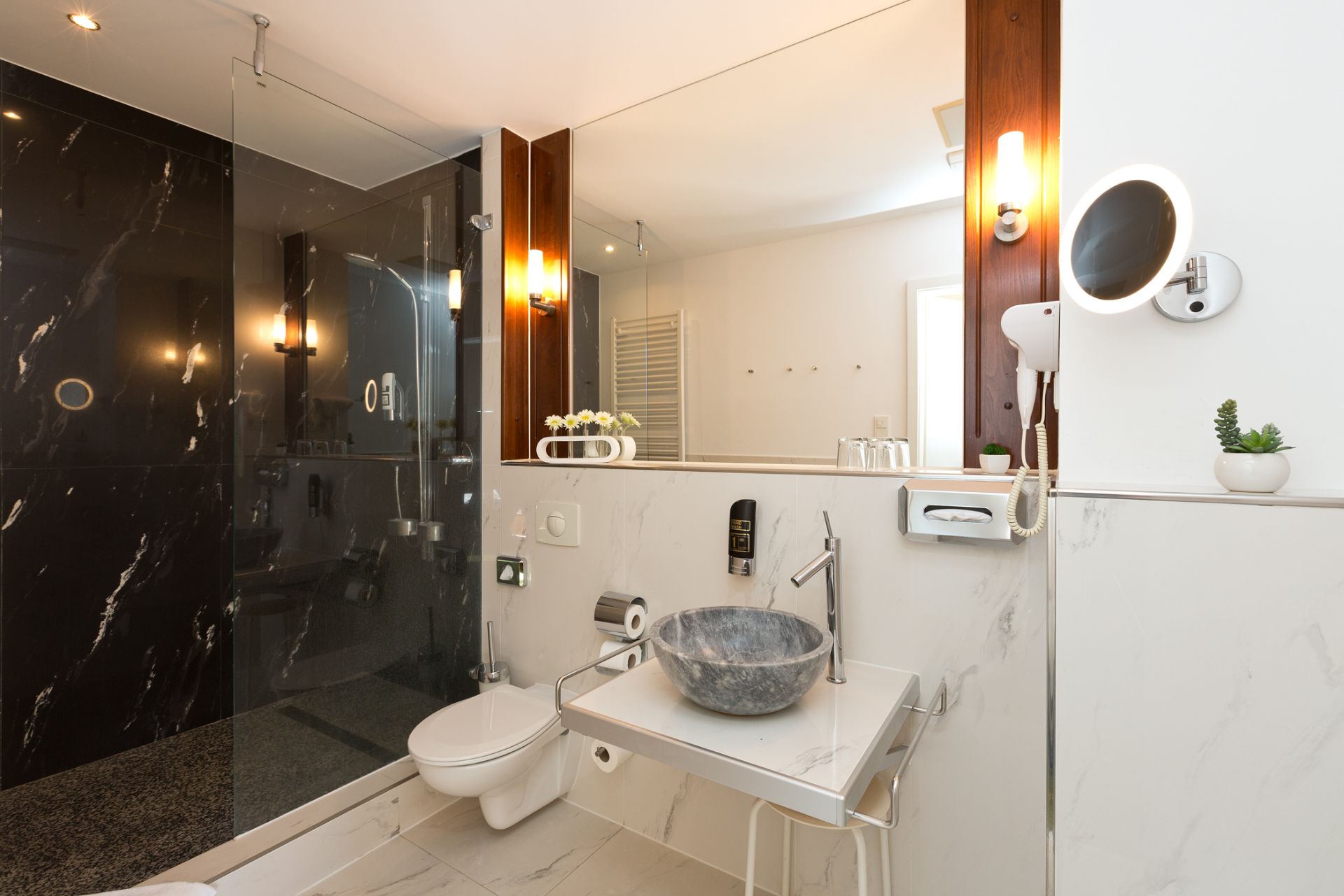 Modernes Bad mit großer Dusche, Waschbecken aus Stein und Wandspiegel.