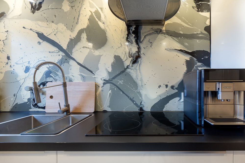Moderne Küchenzeile mit Spüle, Herd, Wasserhahn, Schneidebrett und Kaffeemaschine.