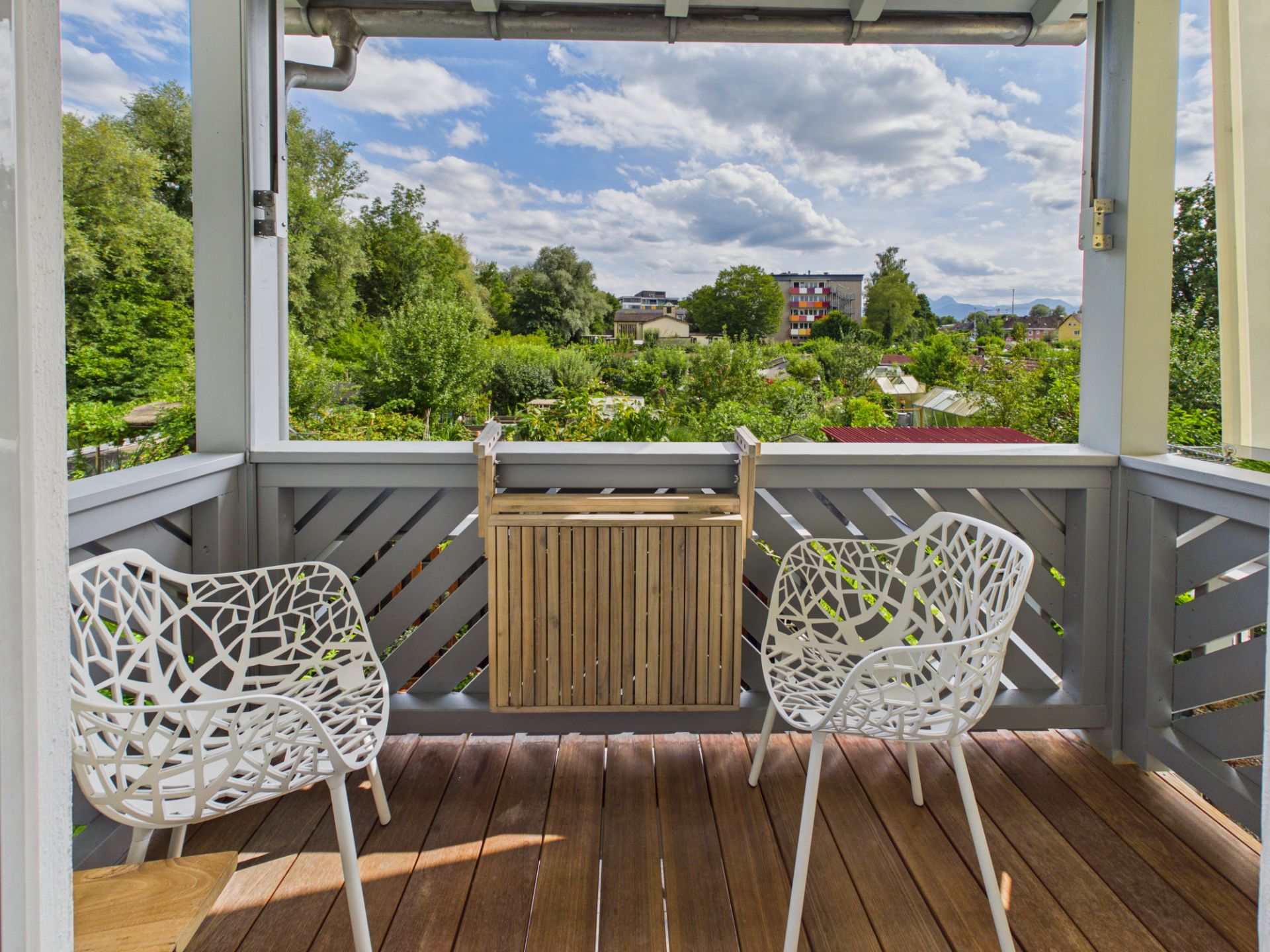 Kleine Terrasse mit zwei weißen Stühlen und Blick ins Grüne.