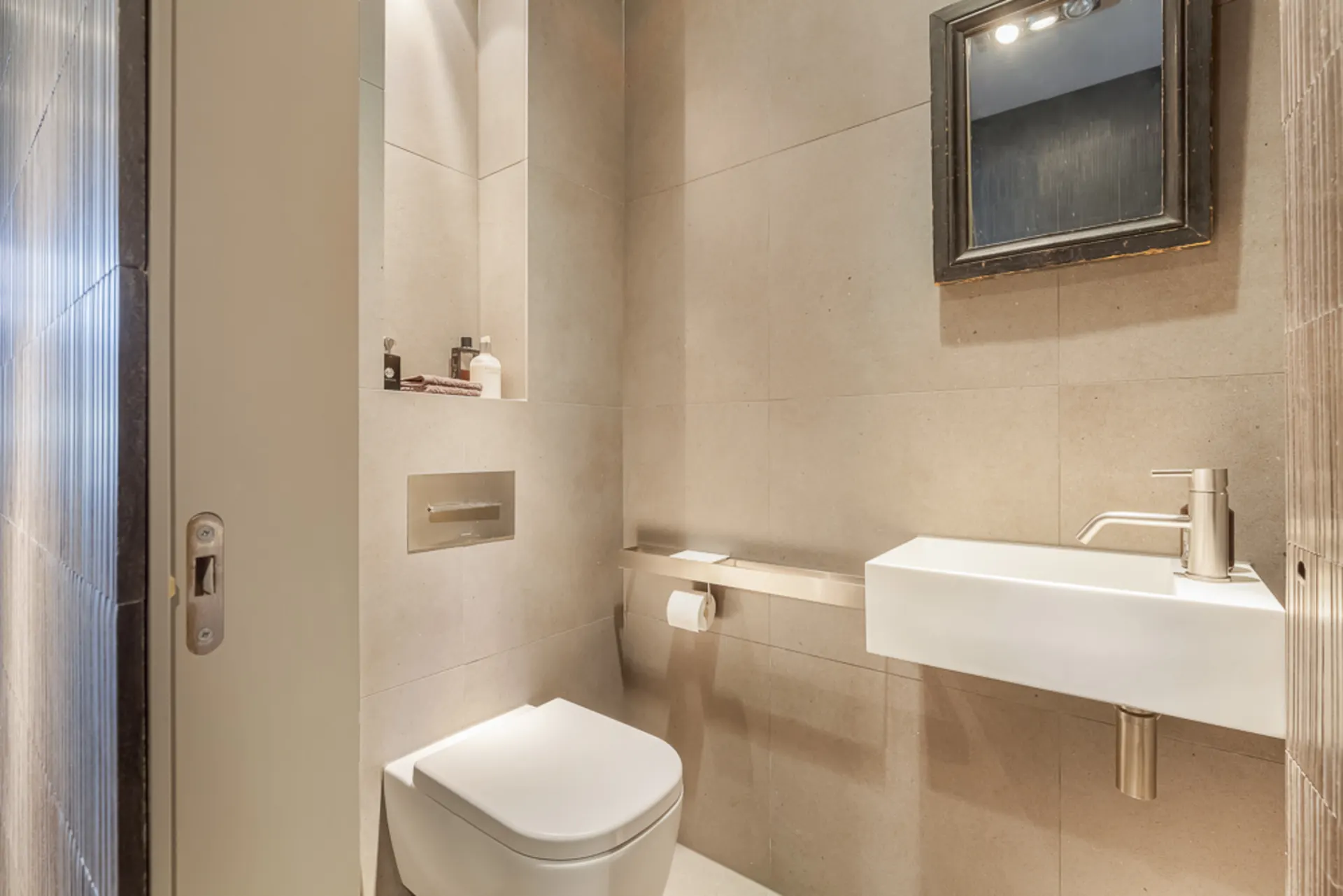 Modernes kleines Bad mit Wandtoilette, rechteckigem Waschbecken und Spiegel.