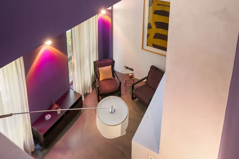 Wohnzimmer mit zwei Sesseln, kleinem Tisch, Sideboard, Vorhängen und moderner Wandkunst.
