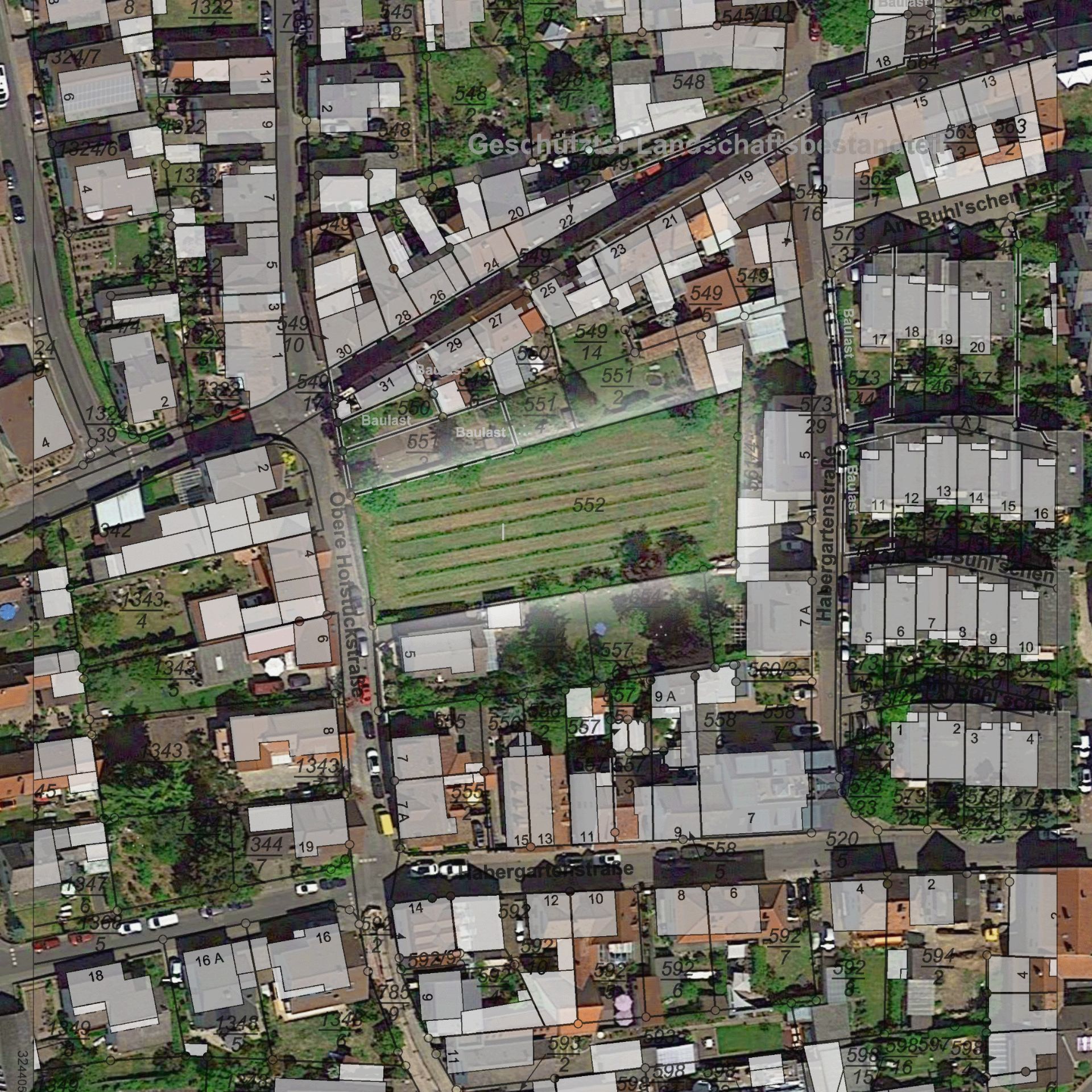 Luftaufnahme eines Wohngebiets mit Häusern, Straßen und einem großen grünen Feld in der Mitte.