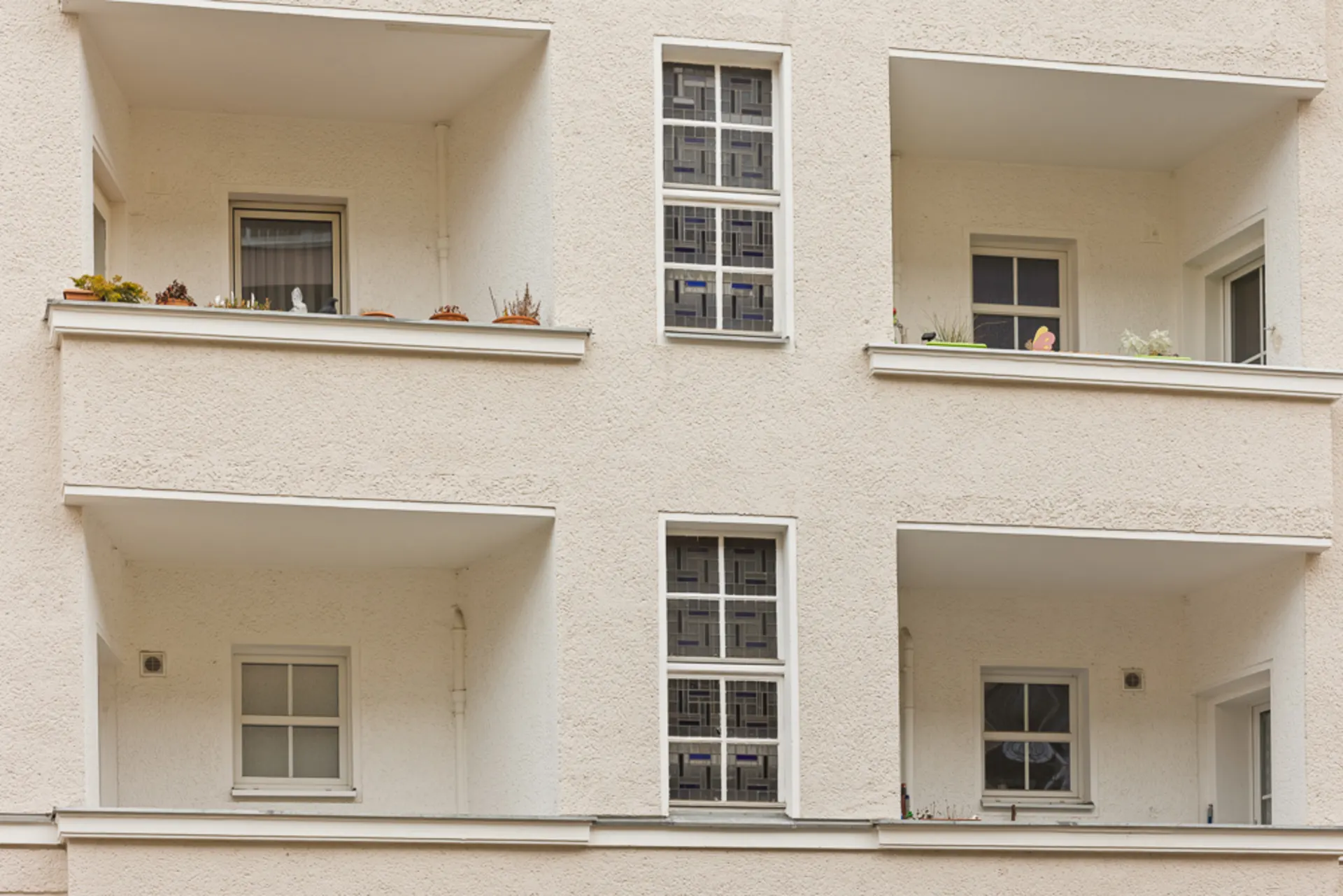 Fassade eines Wohngebäudes mit vier Balkonen und zentralen Fenstern.