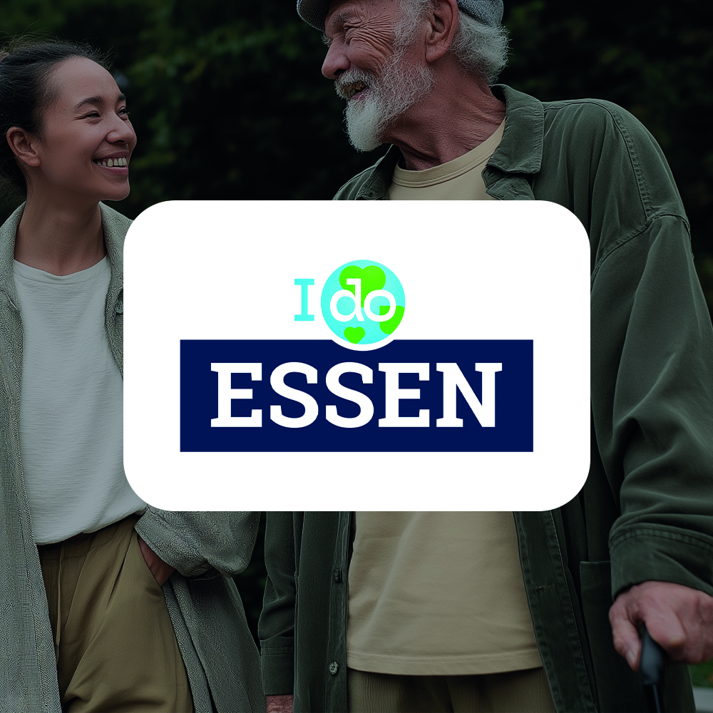 Zwei lächelnde Personen stehen im Freien mit grünem Hintergrund.