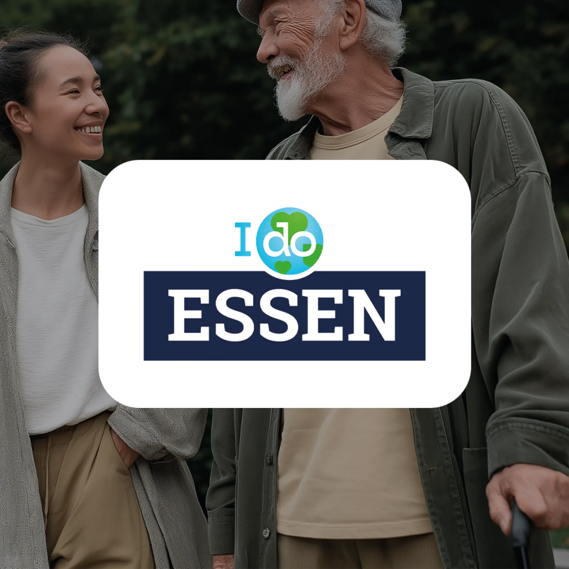 Zwei lächelnde Personen stehen im Freien mit grünem Hintergrund.