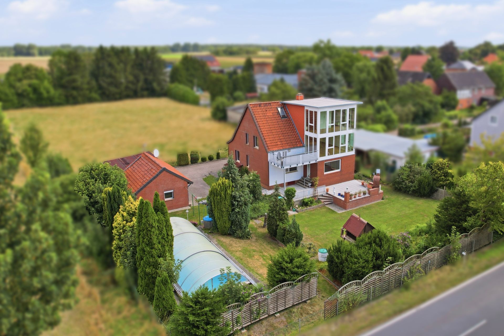 Modernes Einfamilienhaus mit Wintergarten, großem Garten und überdachtem Pool im Grünen.