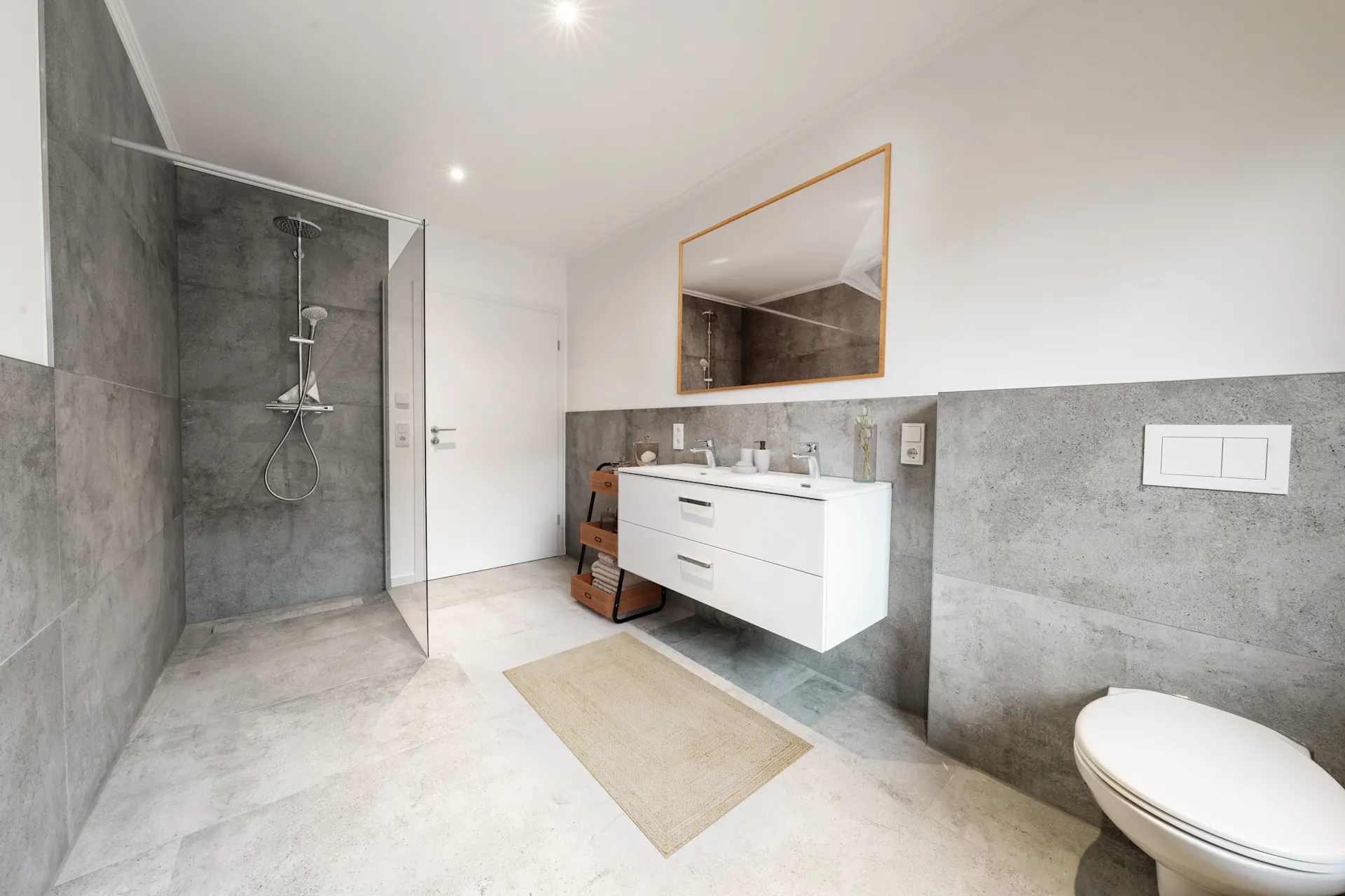 Modernes Badezimmer mit ebenerdiger Dusche, Doppelwaschbecken und Wandtoilette.