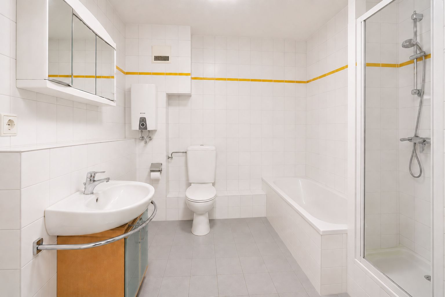 Helles Badezimmer mit Waschbecken, Toilette, Badewanne und Dusche, alles auf weißen Fliesen.