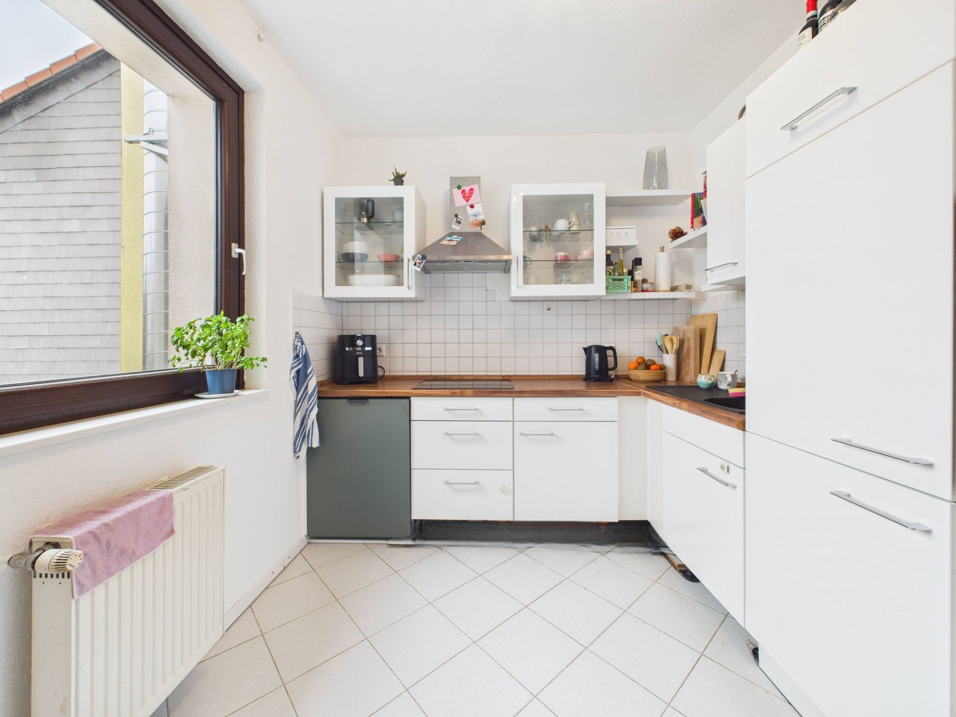 Helle Küche mit weißen Schränken, großem Fenster und Holzarbeitsplatte.