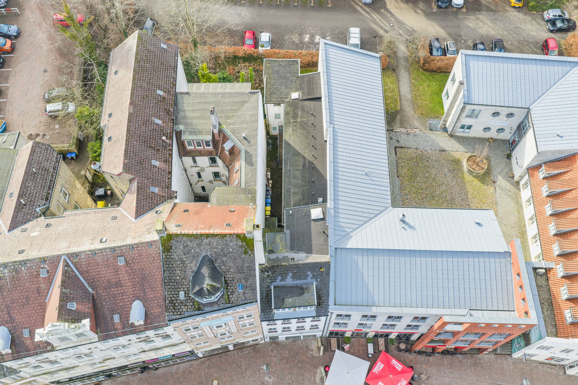 Luftaufnahme von mehreren Wohngebäuden mit Innenhof, parkenden Autos und Wegen.
