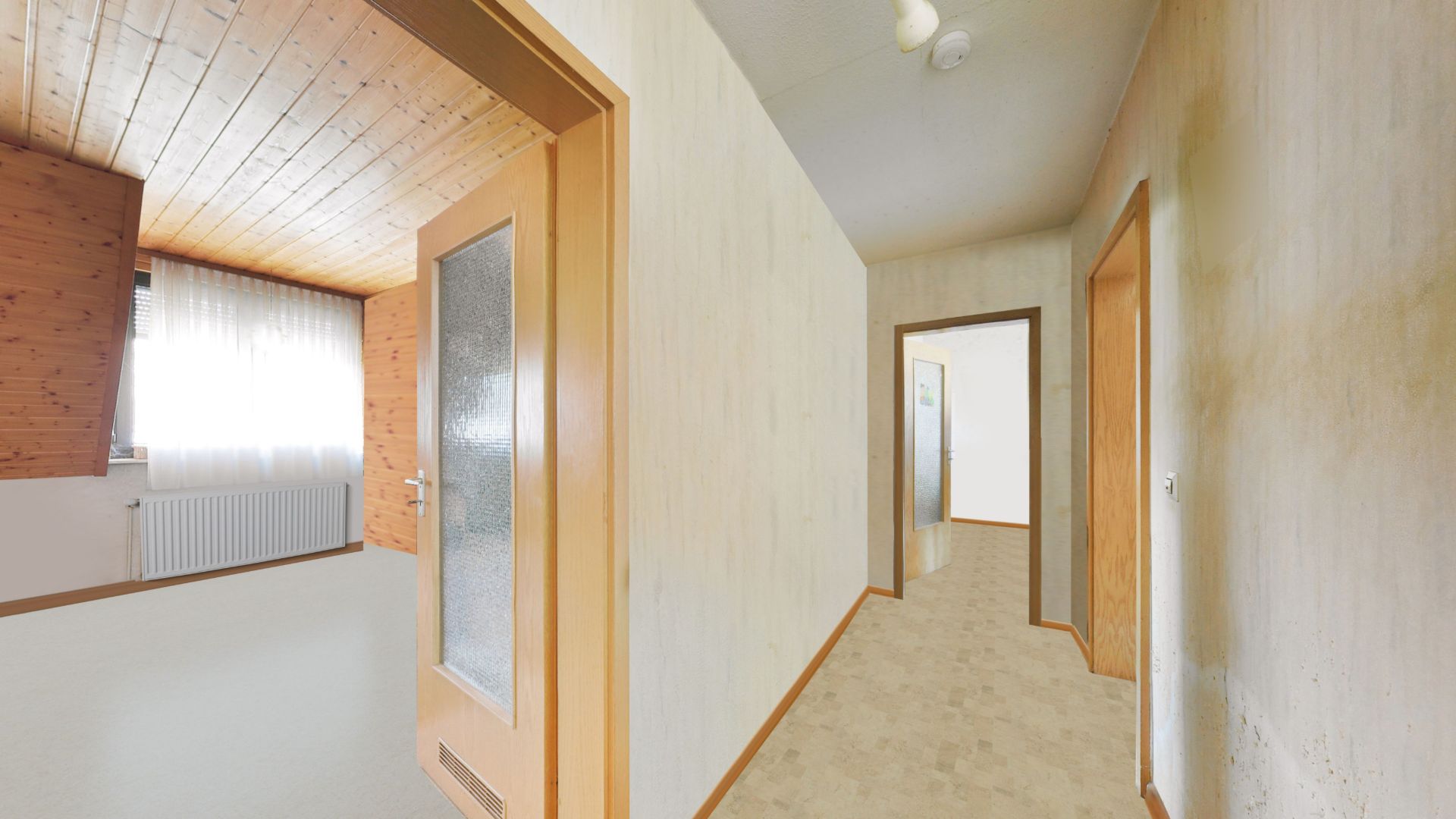Heller Flur mit Holztüren, einem Zimmer links und sichtbarem Fenster mit weißen Vorhängen.