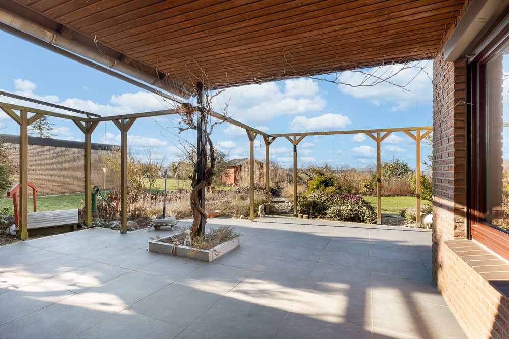 Überdachte Terrasse mit Holzdach und Rankgitter, Blick auf Garten und Pflanzen.