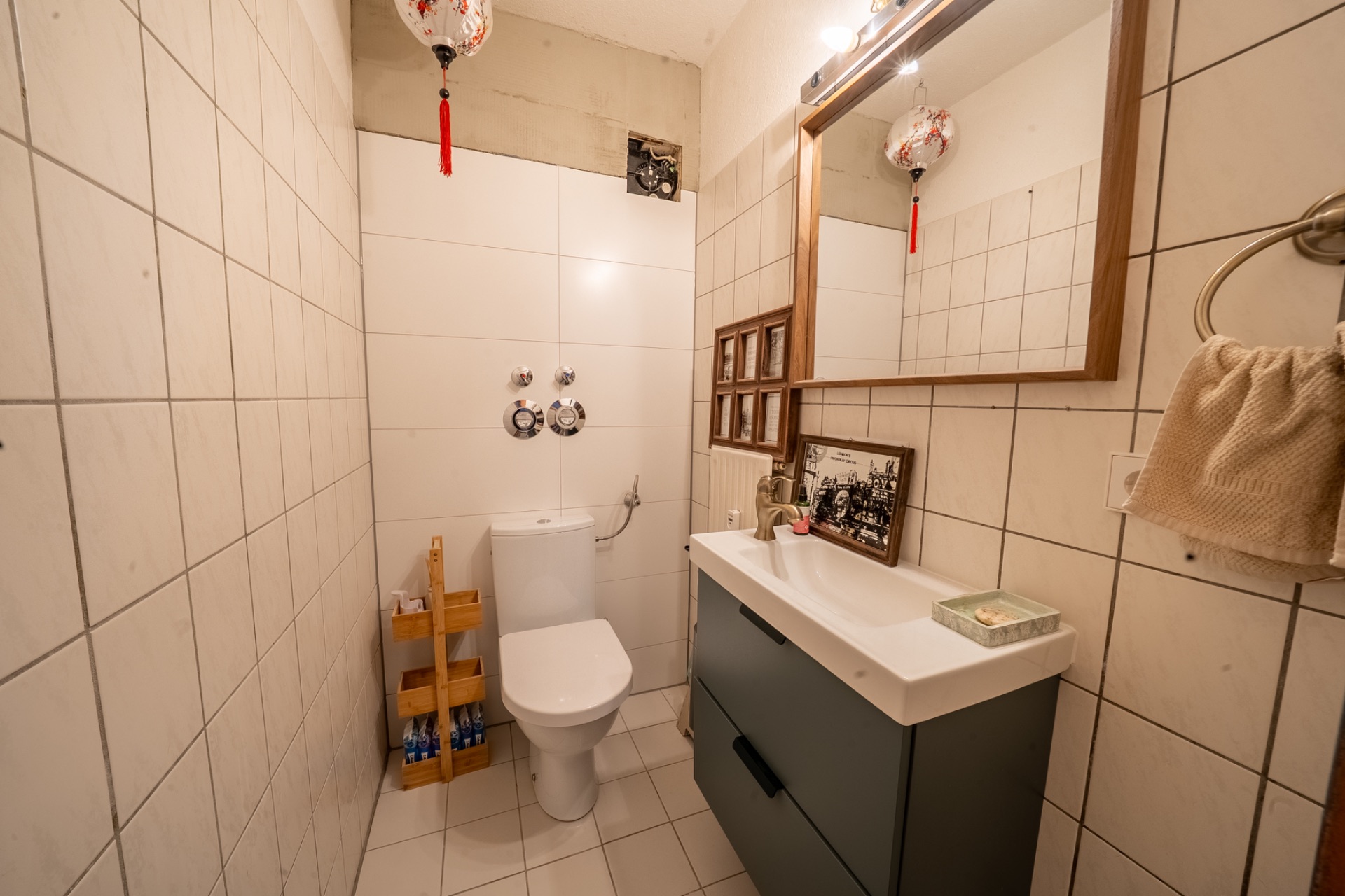 Modernes Badezimmer mit Toilette, Waschbecken, Spiegel und Handtuchhalter an der Wand.
