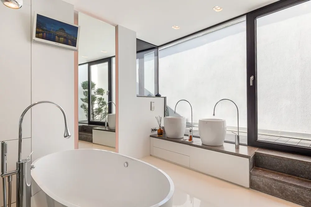 Modernes Badezimmer mit freistehender Badewanne und großen Fenstern.