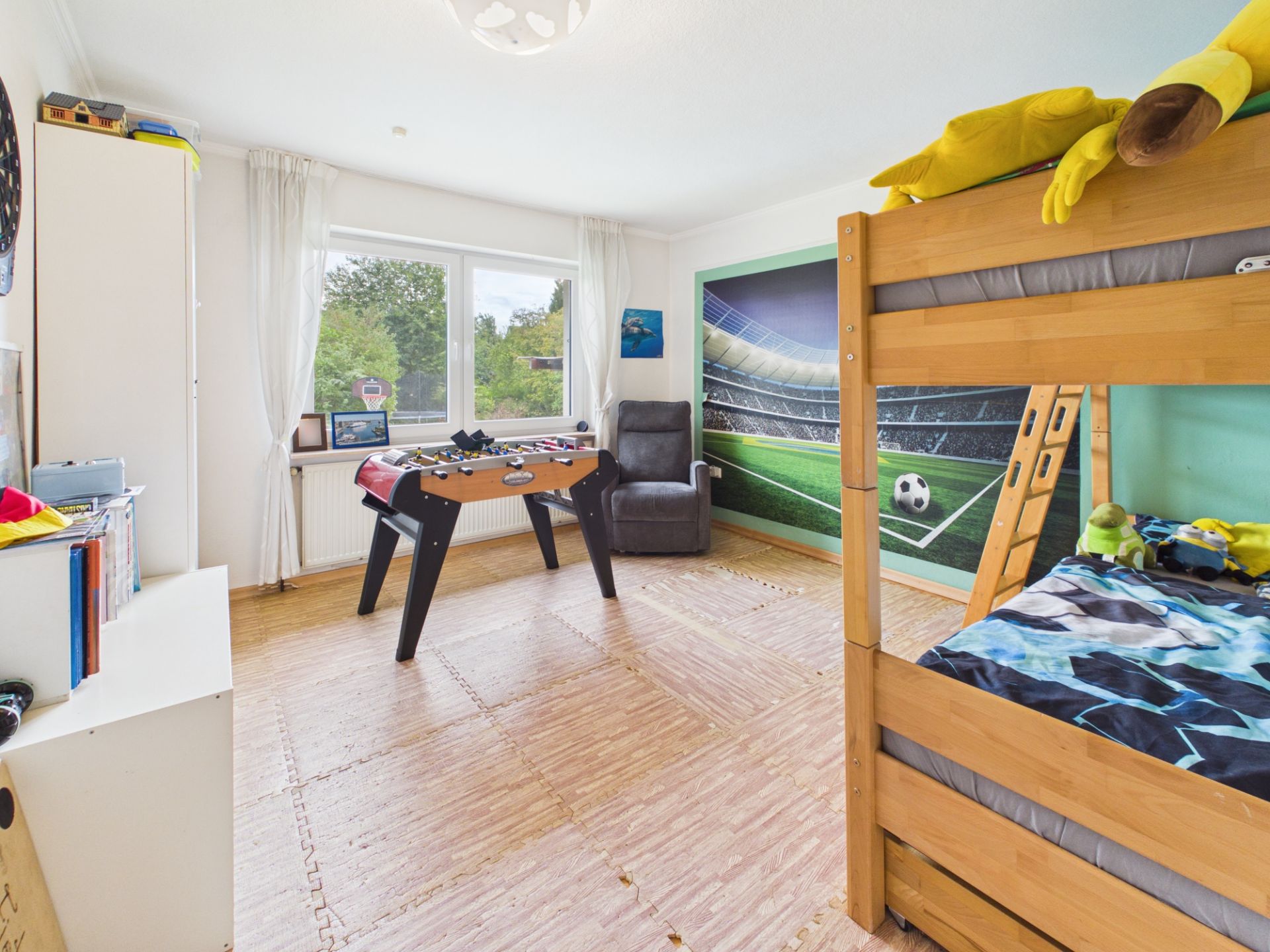 Kinderzimmer mit Etagenbett, Tischkicker und Fußballmotiv an der Wand.