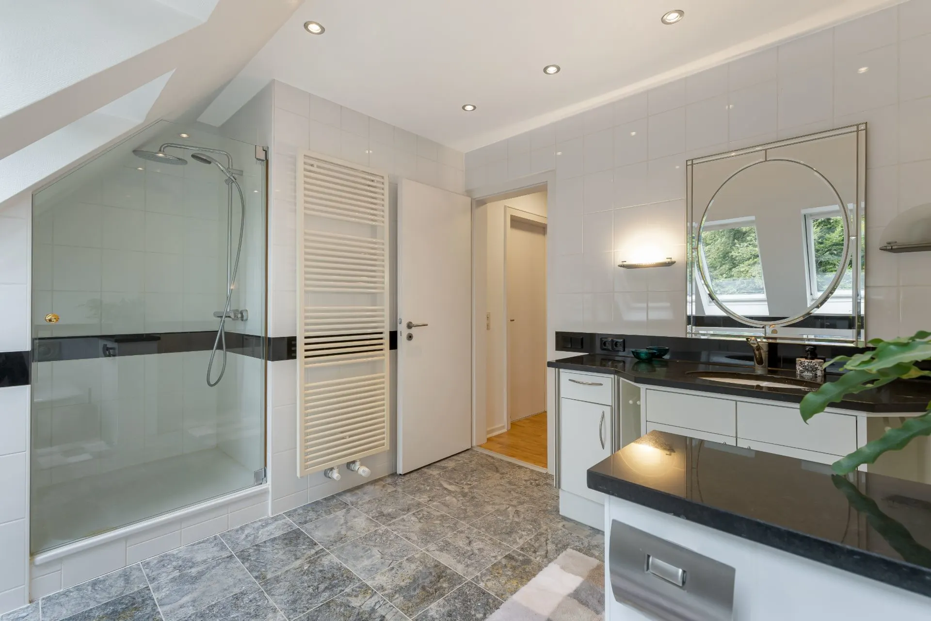 Modernes Badezimmer mit Dusche, großem Spiegel, Waschbecken und Fliesenboden.