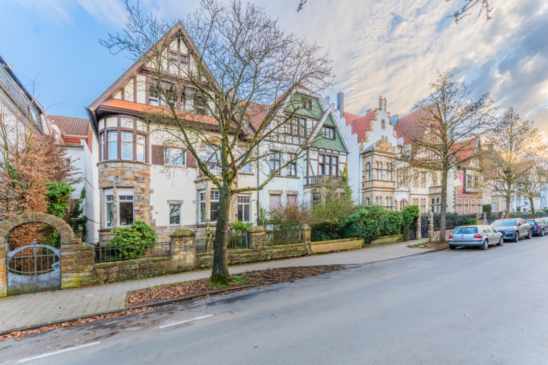 Reihe von Wohnhäusern mit Vorgärten und Bäumen entlang einer ruhigen Straße.
