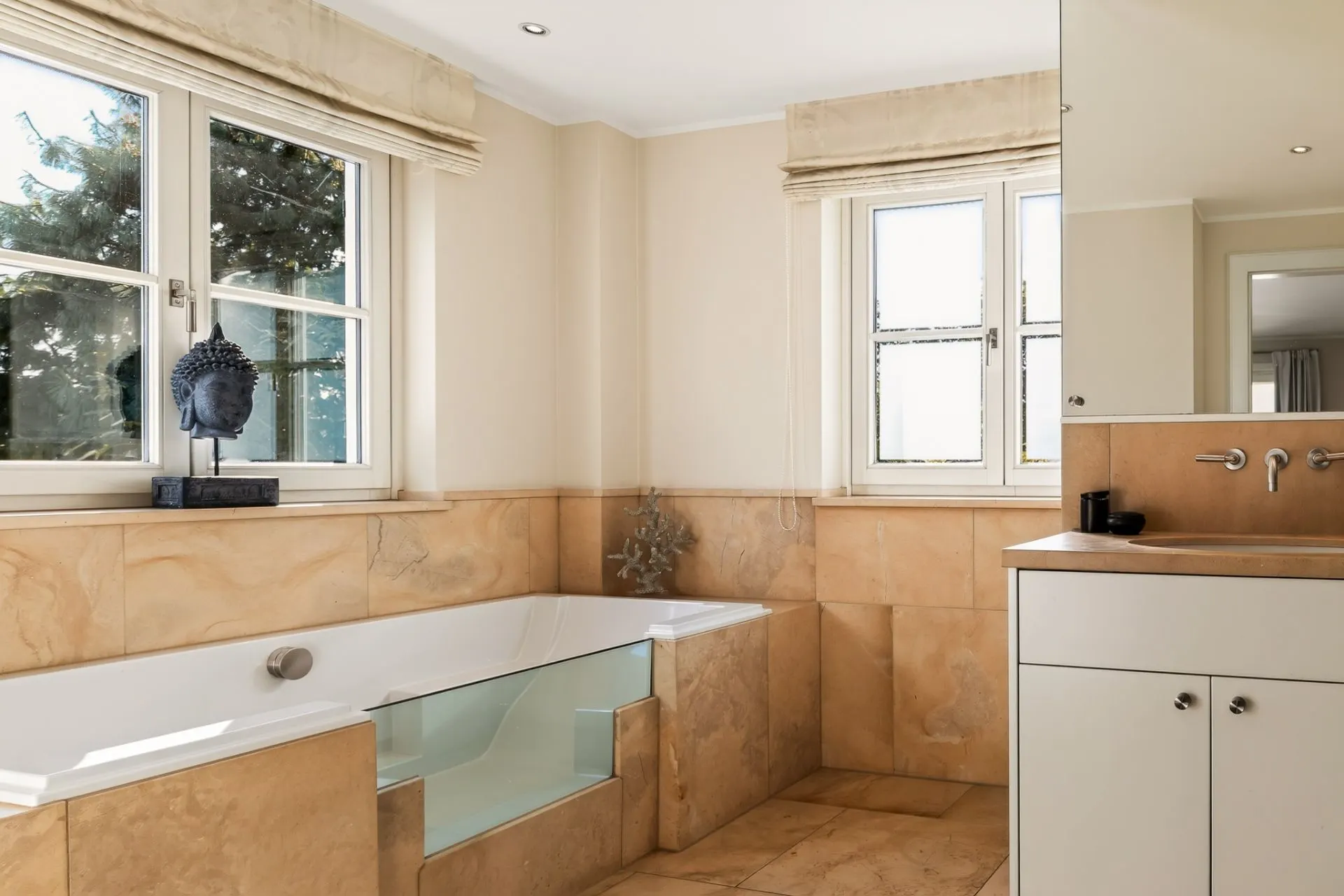 Modernes Badezimmer mit Badewanne, großen Fenstern und beigem Fliesenboden.