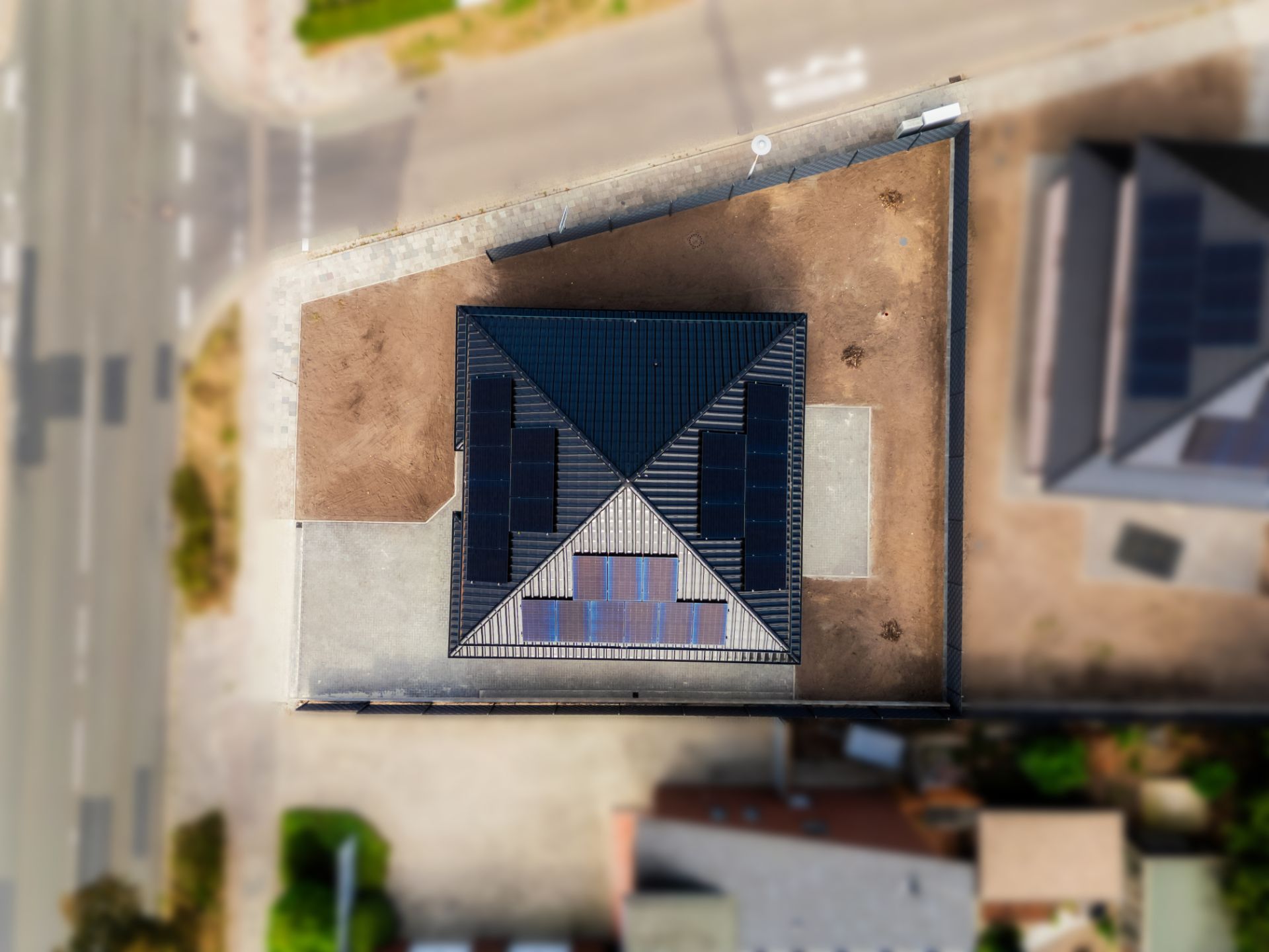 Draufsicht auf ein Haus mit Solarpanels auf dem Dach und umliegendem Hof.