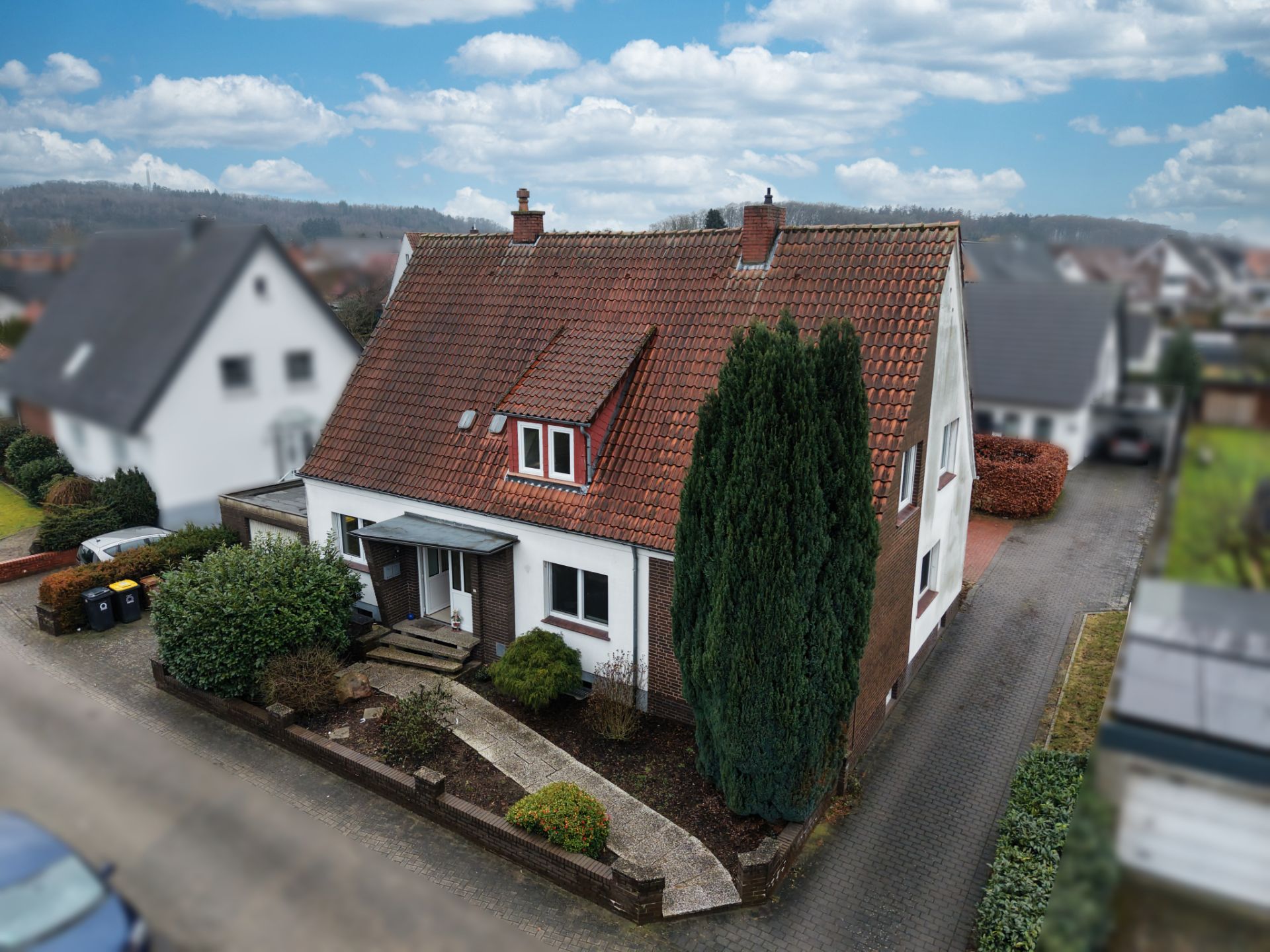 Zweistöckiges Haus mit rotem Dach, kleinem Vorgarten und gepflastertem Weg.