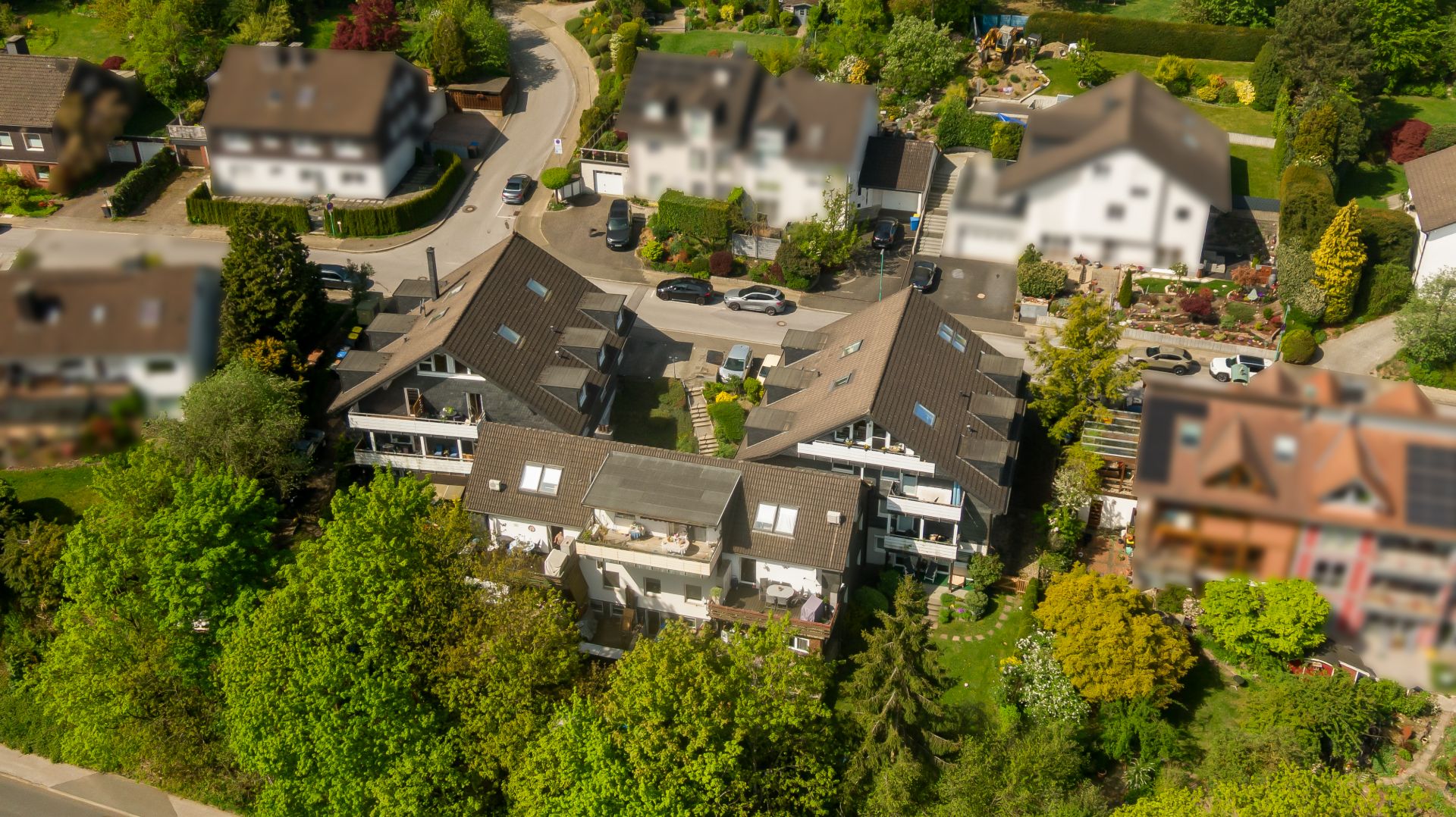 Luftaufnahme von Wohnhäusern mit Balkonen und umgebenden Bäumen in einem grünen Wohngebiet.