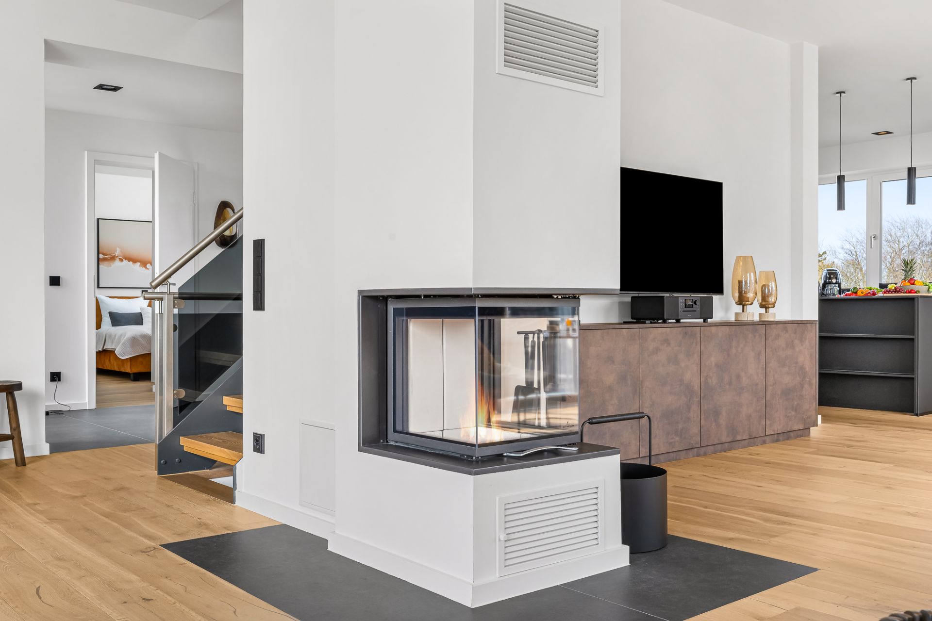 Modernes Wohnzimmer mit Kamin, Fernseher und Holzfußboden.