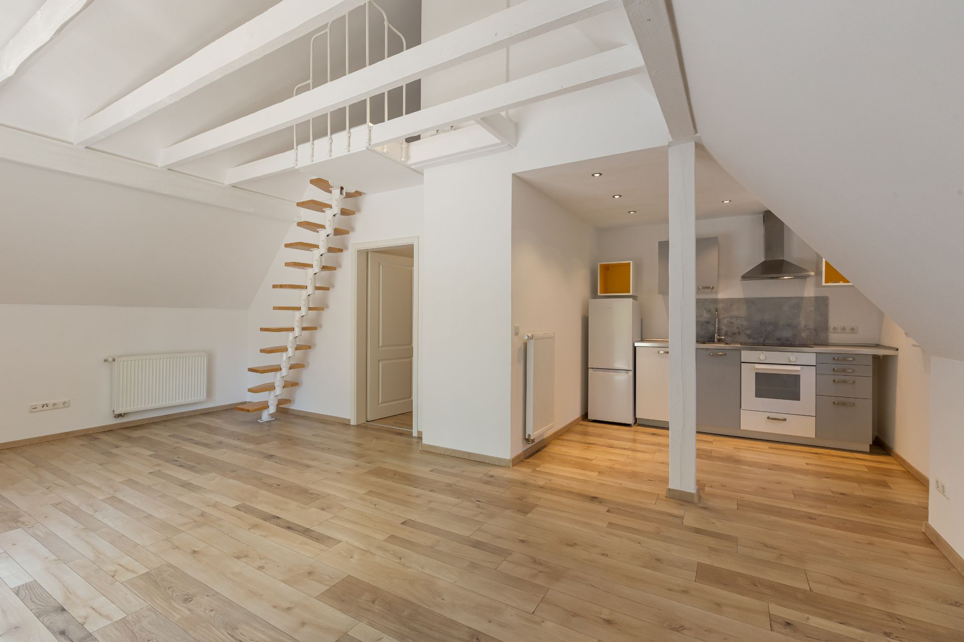Helle Wohnung mit Holzfußboden, Küche, Treppe zur Galerie und offenem Wohnbereich.