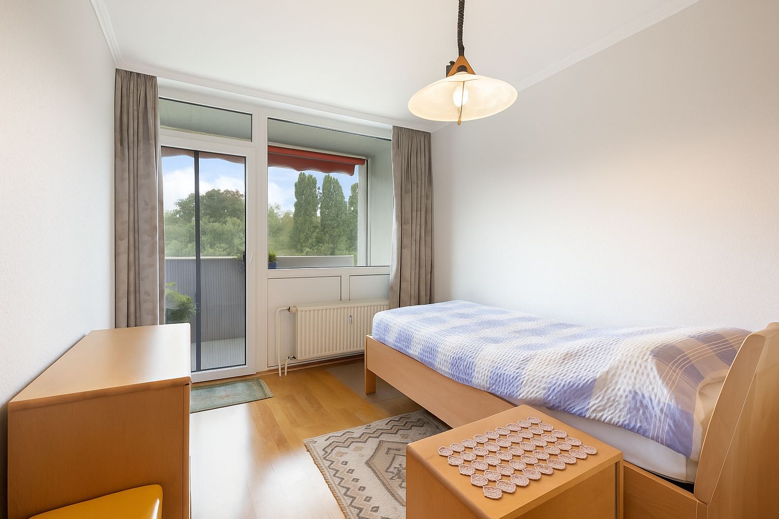 Helles Einzelzimmer mit Bett, Schreibtisch, Stuhl und Zugang zum Balkon.