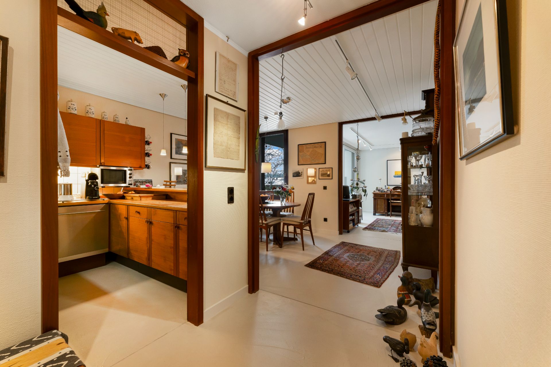 Flur mit Blick in Küche und Esszimmer, viele Holzmöbel und Dekorationen.