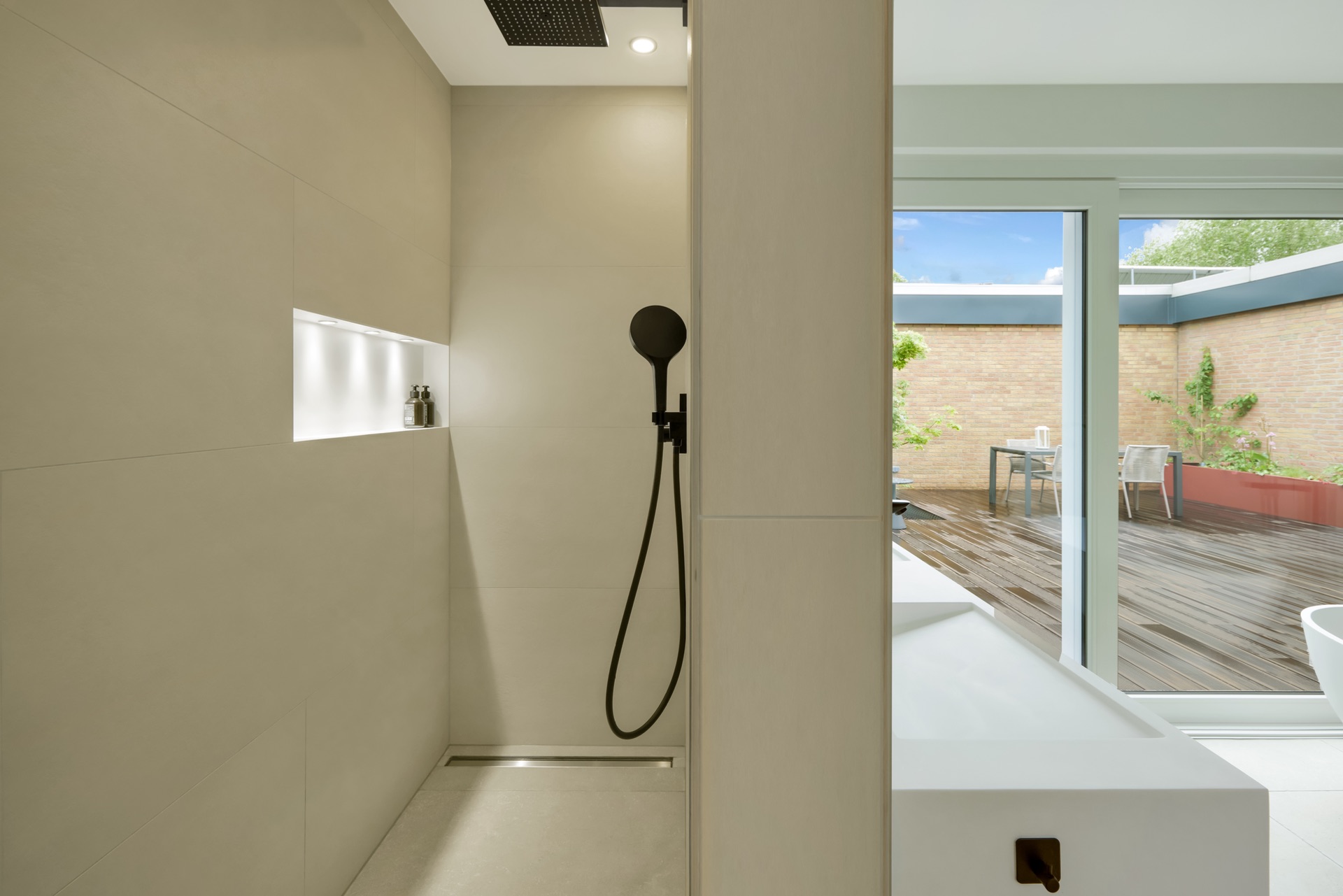 Modernes Badezimmer mit offener Dusche und Blick auf eine Terrasse mit Holzboden.