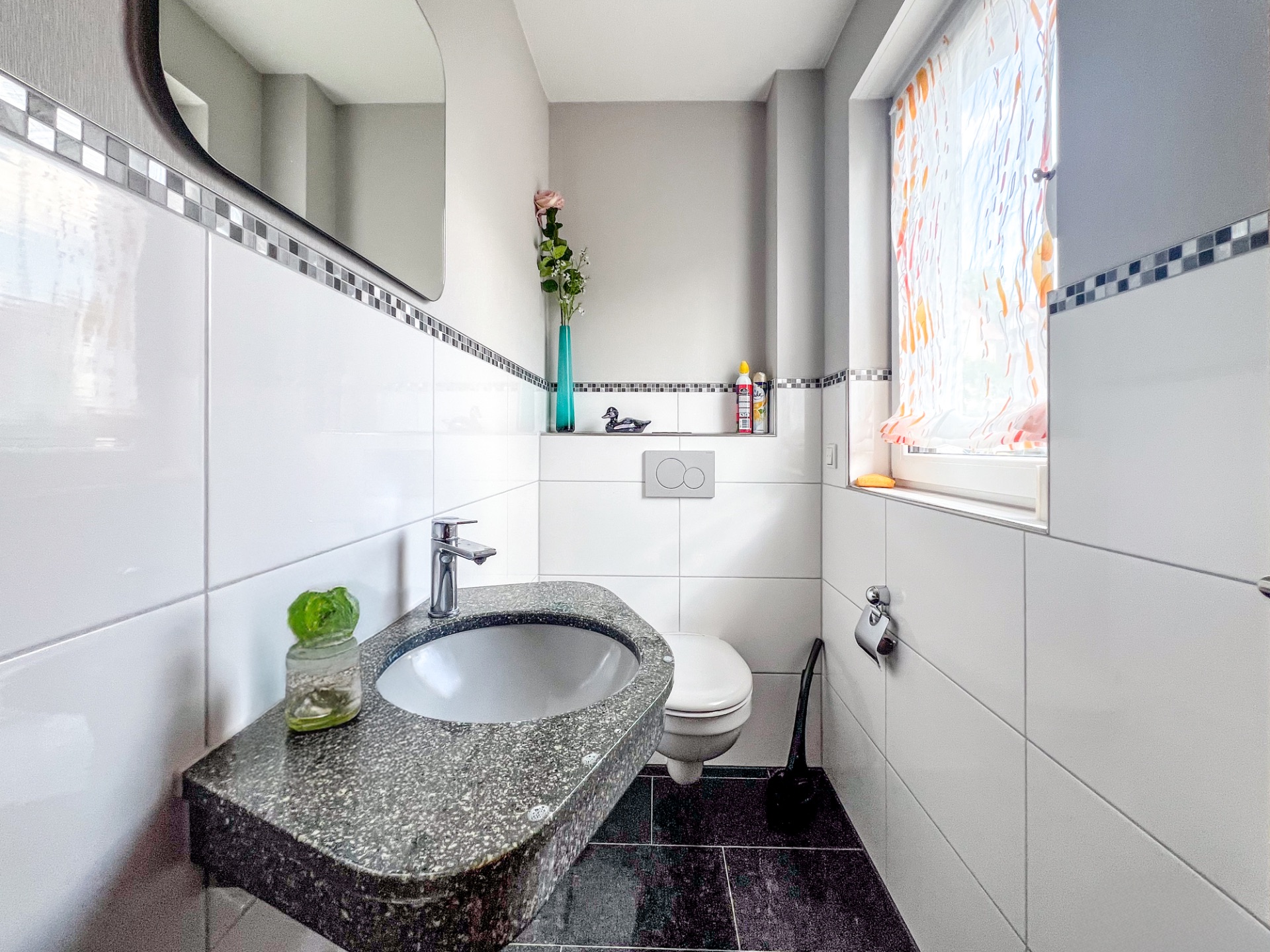 Modernes, kleines Badezimmer mit Waschbecken, Toilette, Spiegel und Fenster.