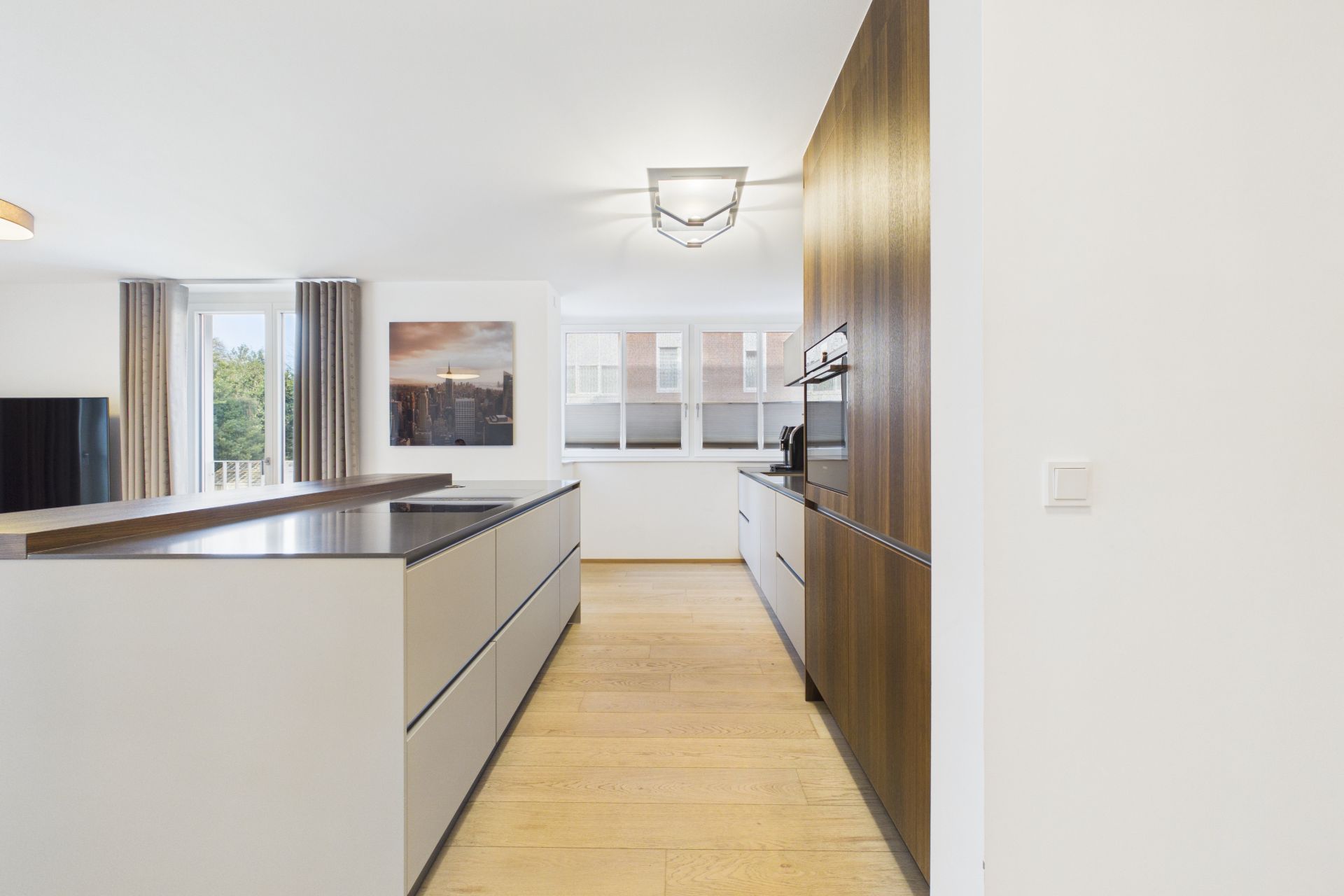 Moderne Küche mit Holzfußboden, Einbauschränken und großen Fenstern.