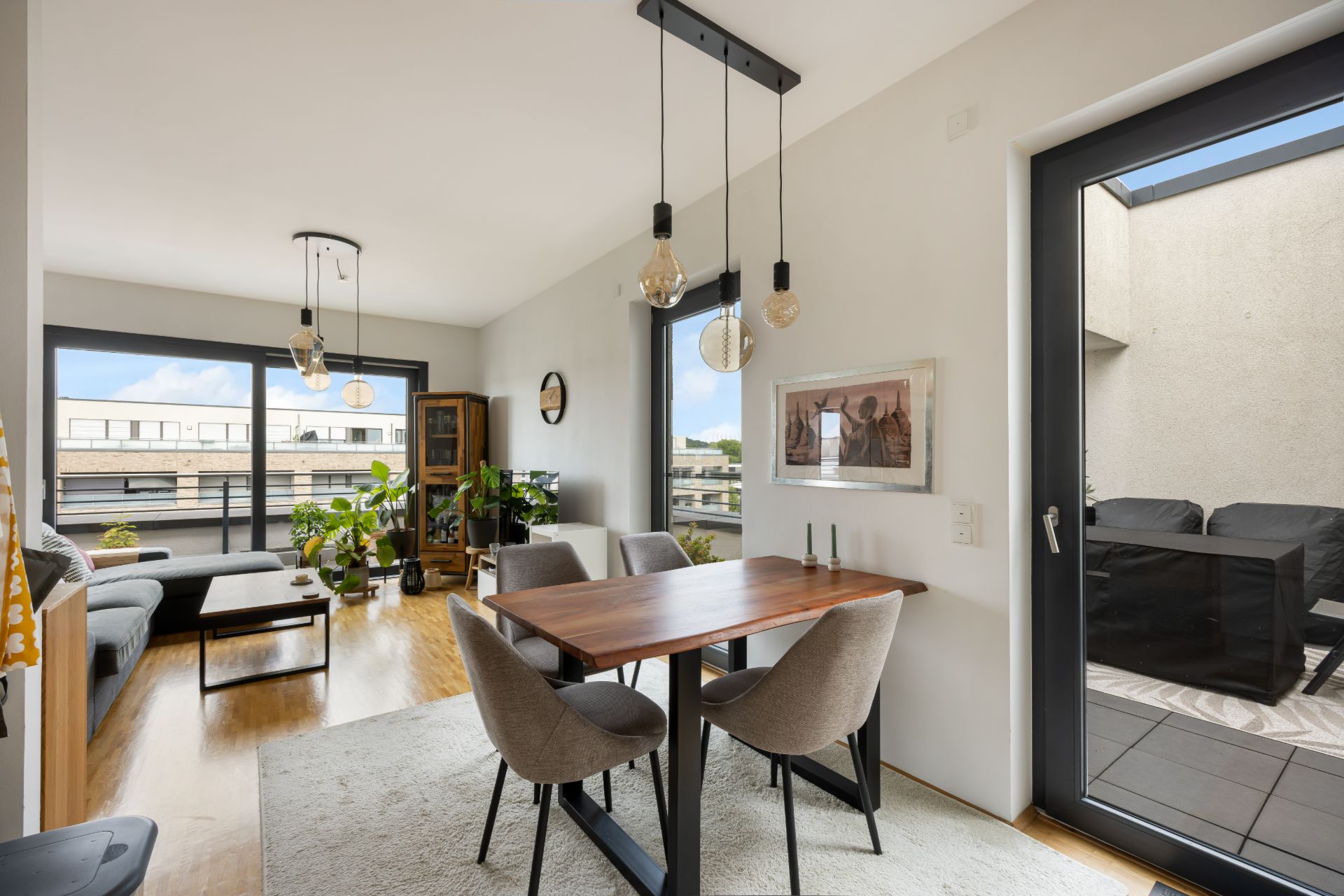 Helles Wohn- und Esszimmer mit Holzboden, großem Fenster, Esstisch und Zugang zur Terrasse.