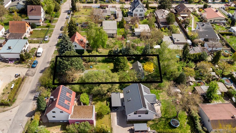 Luftaufnahme eines Grundstücks in einem Wohngebiet, mit Bäumen und kleinem Gebäude, schwarz umrandet.