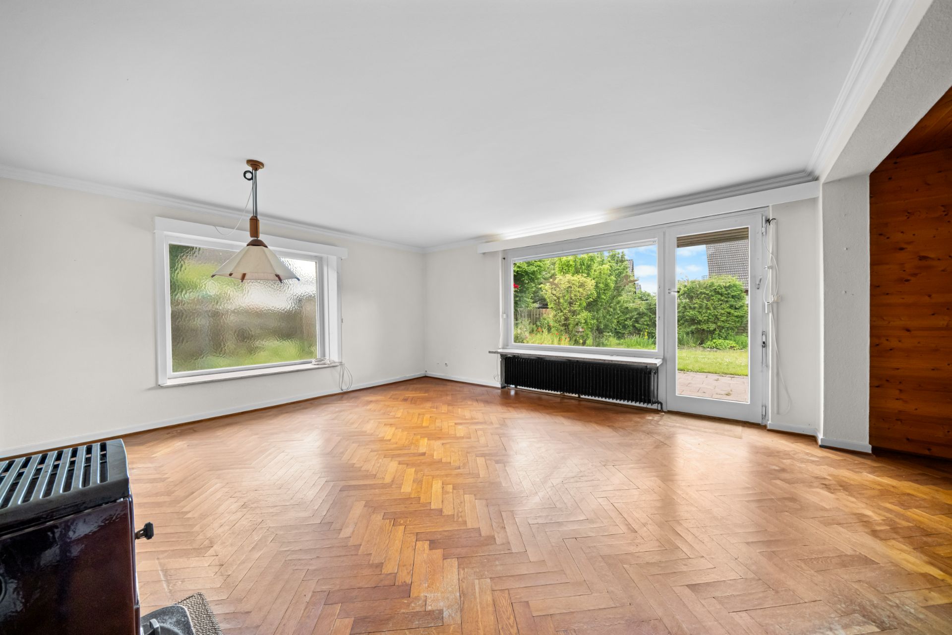 Helles Wohnzimmer mit Parkettboden, großen Fenstern und Tür zum Garten.