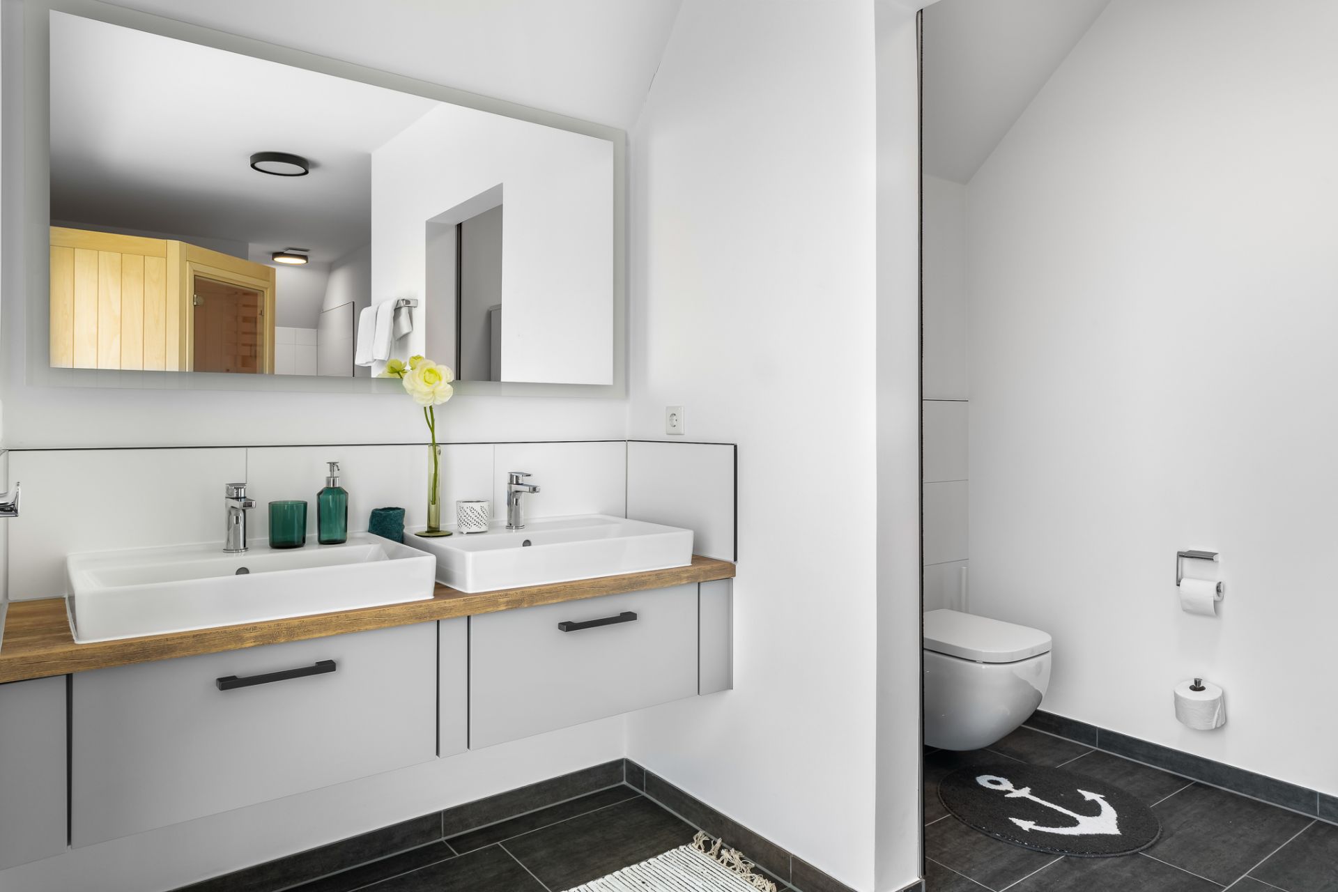 Modernes Badezimmer mit zwei Waschbecken, großem Spiegel und separatem WC-Bereich.