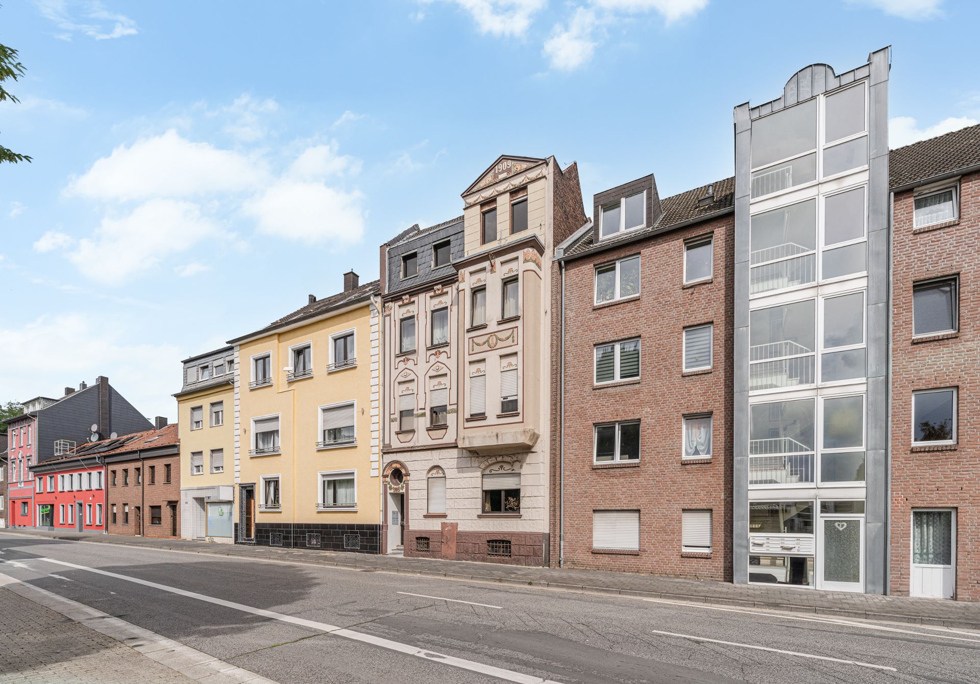 Mehrere Wohnhäuser in einer Straße mit unterschiedlichen Fassaden und Farben.