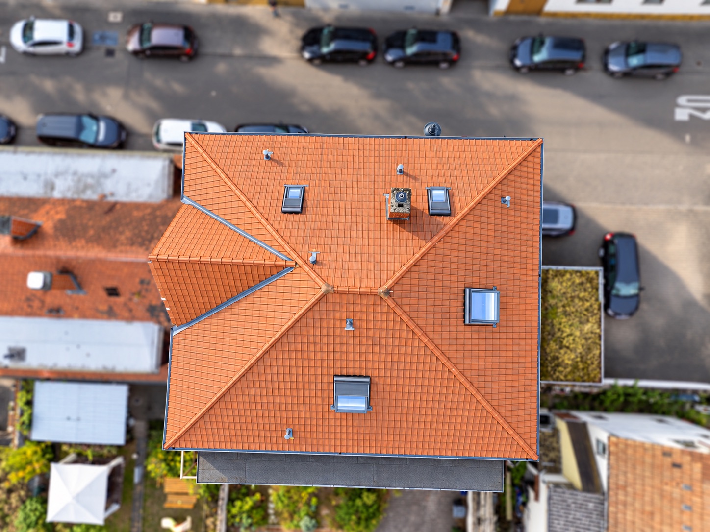 Draufsicht auf ein Haus mit rotem Ziegeldach und mehreren Dachfenstern.