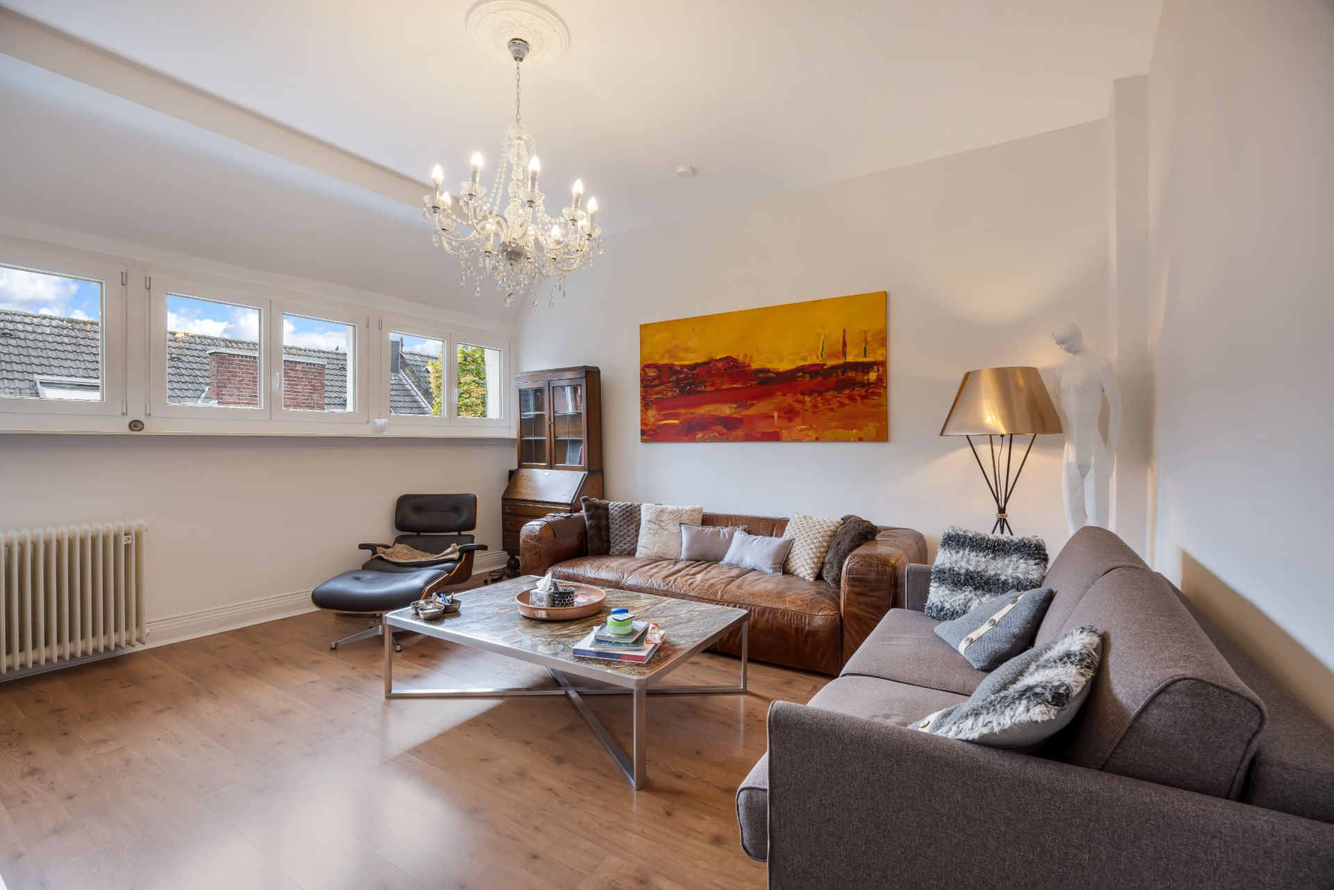 Helles Wohnzimmer mit Kronleuchter, zwei Sofas, Couchtisch und großem Wandbild.