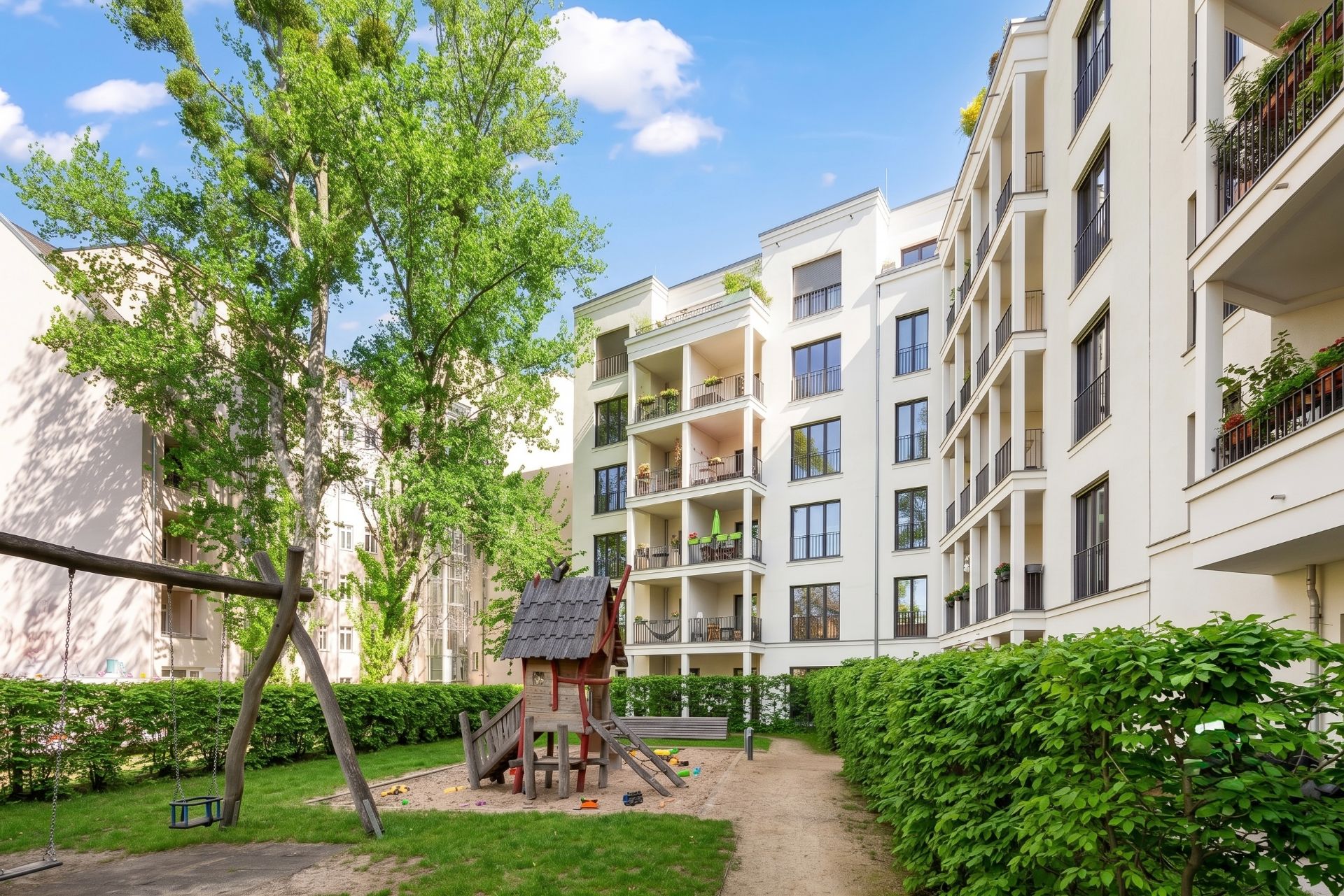Innenhof mit Spielplatz und mehrstöckigen Wohnhäusern im Hintergrund.