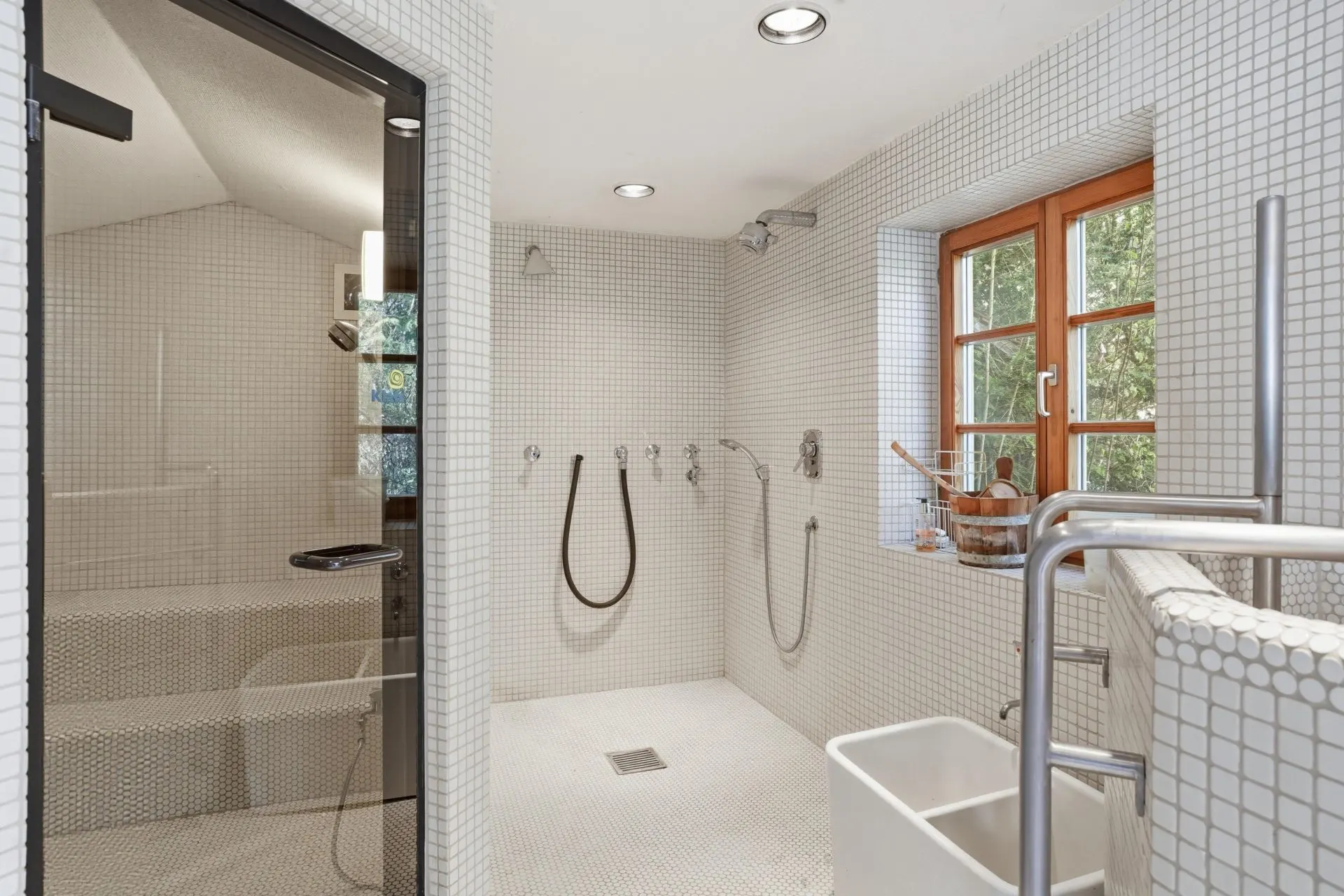 Modernes Badezimmer mit großer Dusche, Fenster, Sauna und weißen Fliesen.