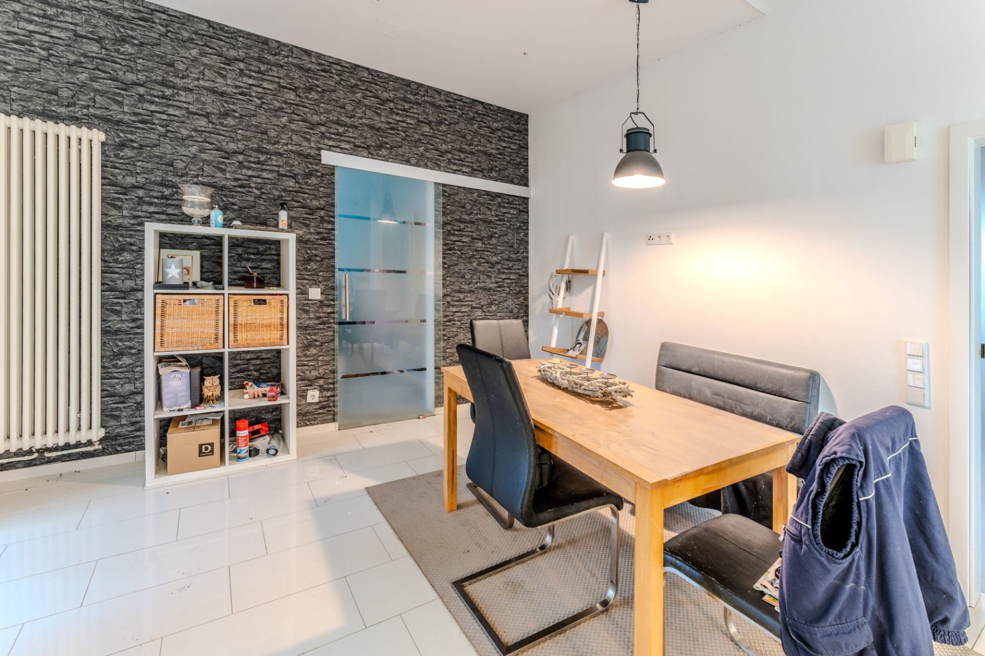Esszimmer mit Holztisch, vier Stühlen, Regal, Teppich und Hängelampe.
