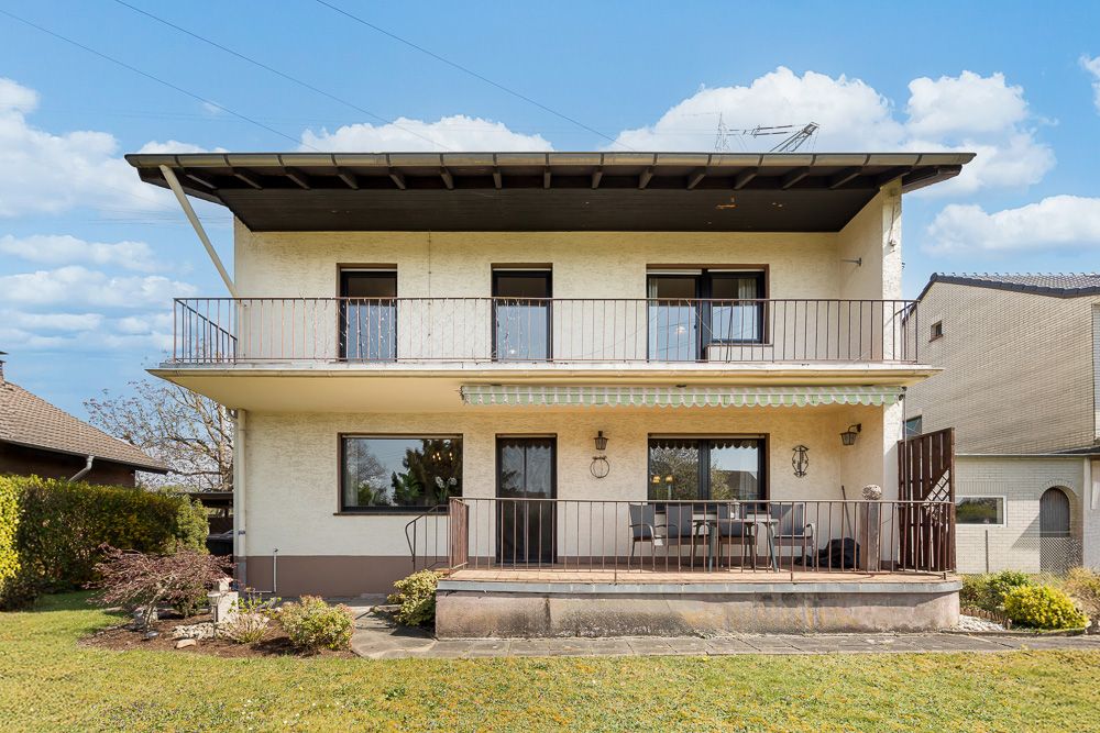 Zweistöckiges Wohnhaus mit Balkon und Terrasse, Garten im Vordergrund.